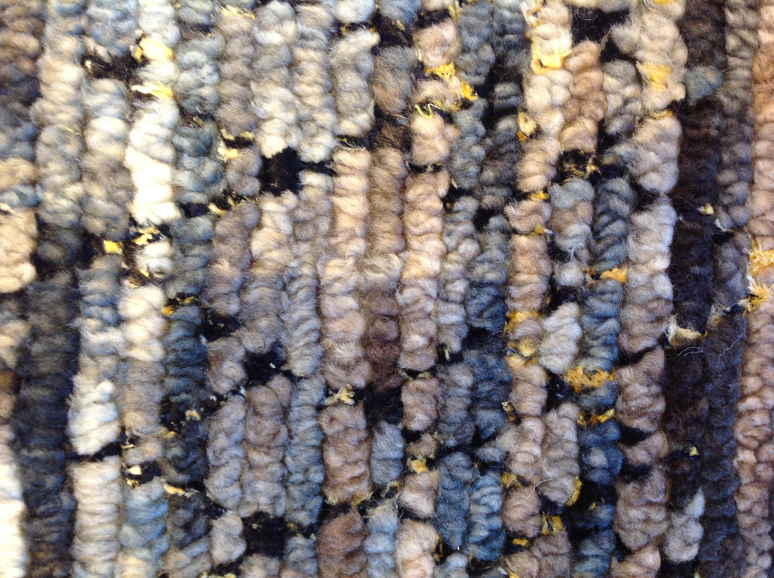 Blau-, Ecru-, Taupe- und Cremetöne mit Crisscross-Muster und gelben Highlights. Die Mischung aus Wolle, Viskose und Baumwolle sorgt für ein angenehmes, genopptes Tragegefühl und ist zudem sehr strapazierfähig. Handgefertigt in Indien mit