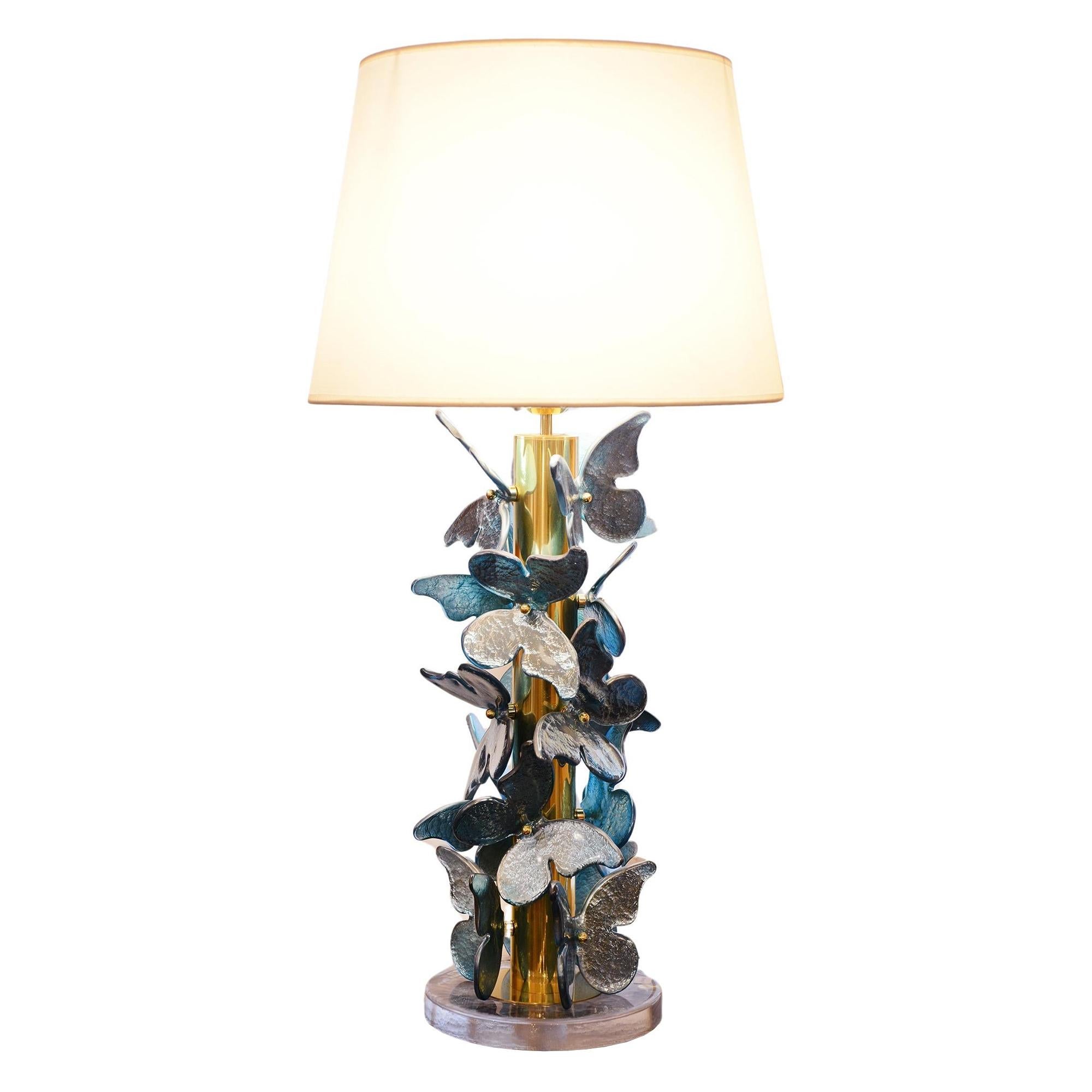 Table Lamp Blue Murano Butterflies with polished
brushed brass base table lamp ornamented with murano
glass butterflies with silver leaf taken under the murano glass.
With white lamp shade included: Diameter 45cm.
Table lamp base: Diameter 27cm,
