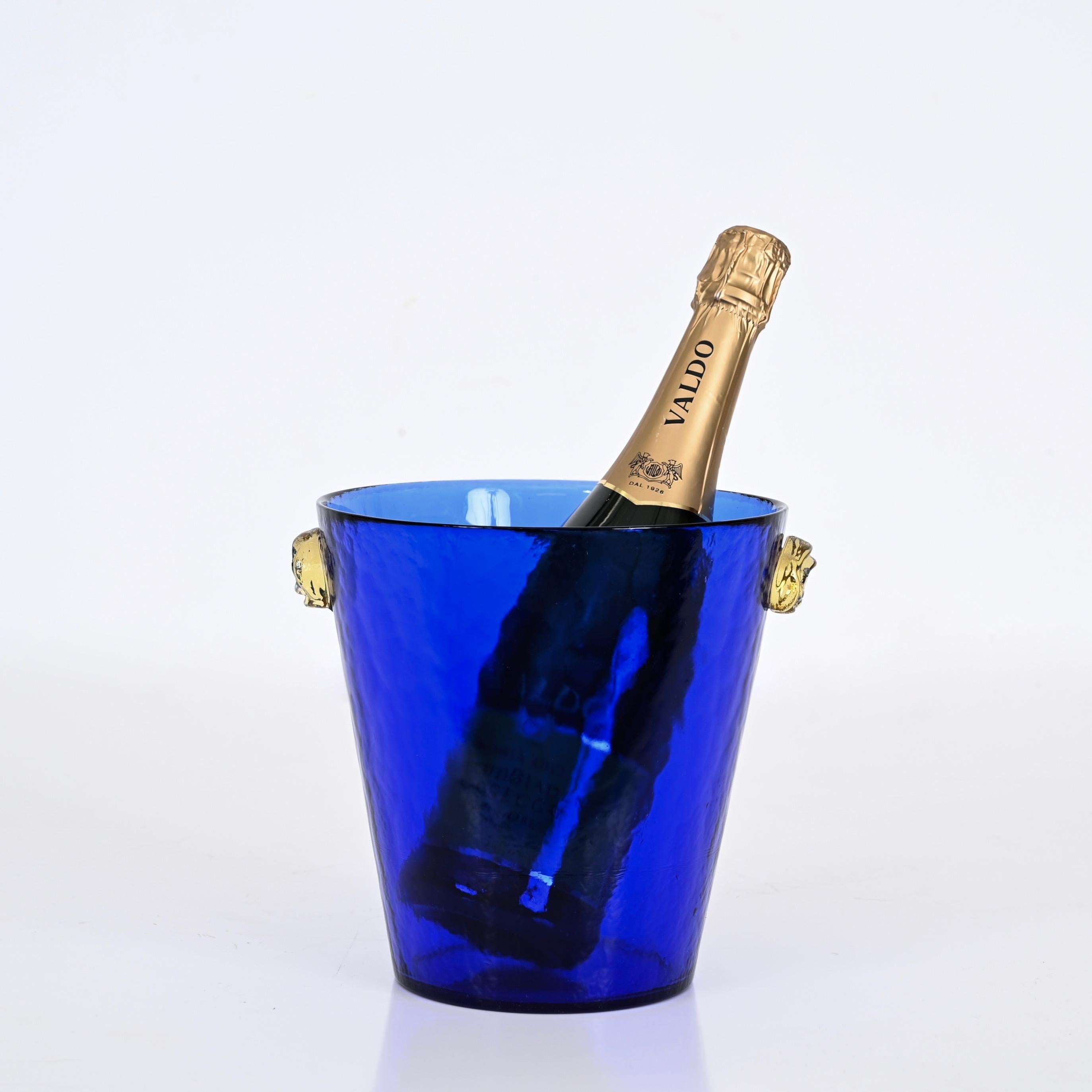 Stunning Ice Bucket in blue Murano glass with gold glass handles. This gorgeous piece was made in Murano, Italy in the 1960s.

This ice bucket is made in an incredibly vibrant blue glass and is completed by two wonderful rose-shaped handles with