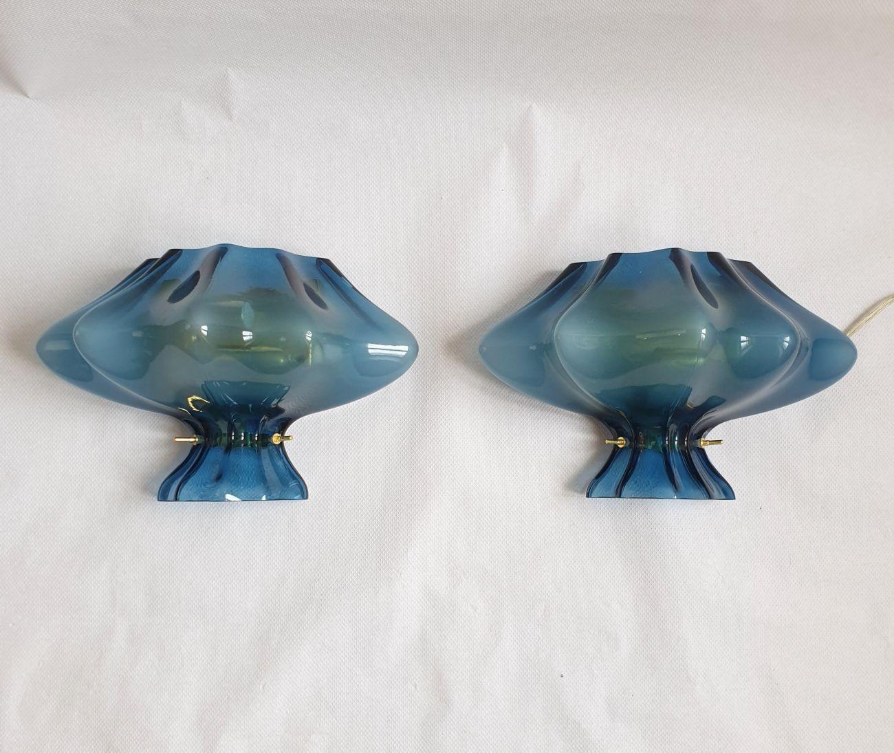 Pair of Murano glass Mid-Century Modern wall sconces, Italy 1980s. Attributed to Cenedese.
The sconces are made of a single piece of Murano glass, from Medium Blue to Light Baby Blue hues.
The Murano glass is translucent. The sconces create a