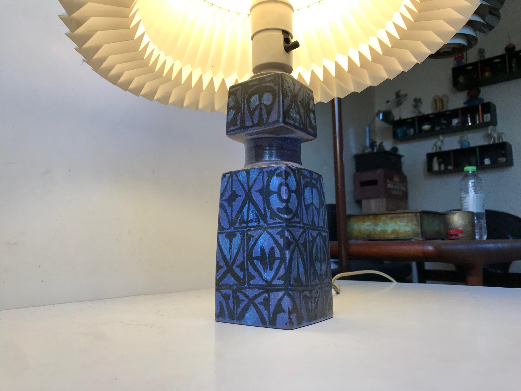 Ceramic table lamp designed by Nils Thorsson for Royal Copenhagen and Fog & Mørup, circa 1970. It features a tactile abstract decor with black on a almost purple tinted blue. The height listed is with bulb and without shade. The shade is a model