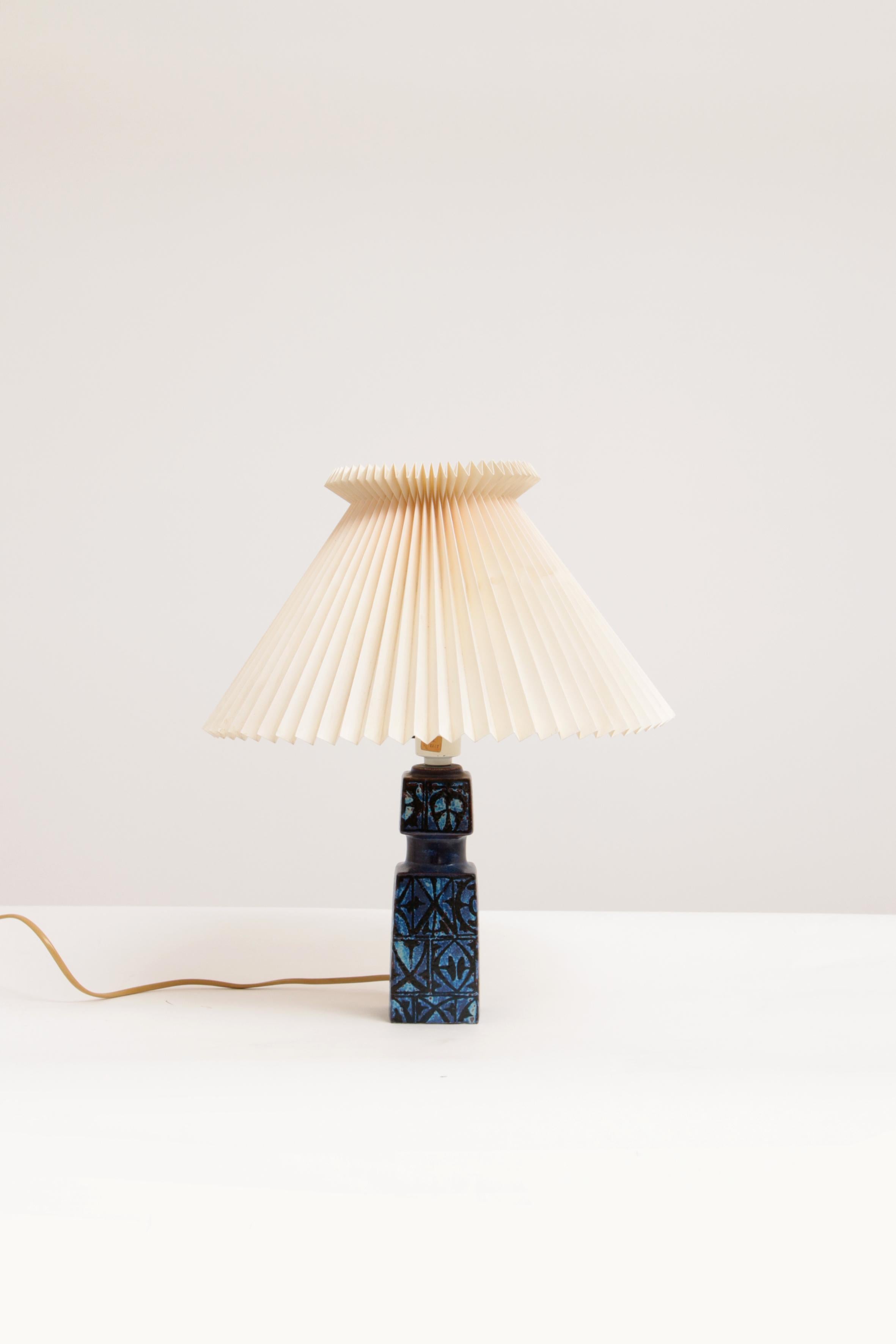 Ceramic table lamp designed by Nils Thorsson for Royal Copenhagen and Fog & Mørup, circa 1970. Model Baca.

It has a tactile abstract decor with black on an almost purple tinted blue. The stated height is with lamp and without shade. The hood is