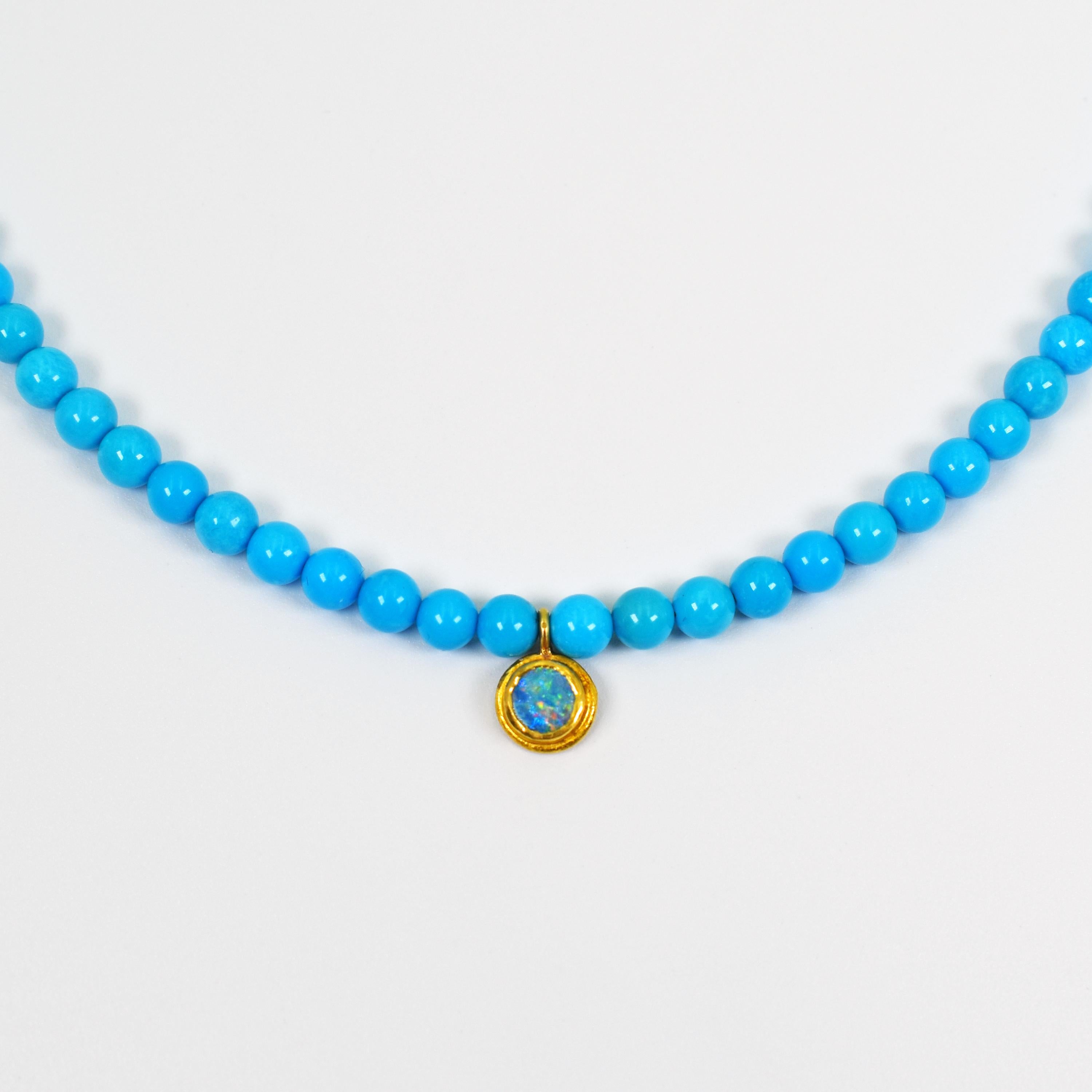 Blue Opal and 22k yellow gold charm pendant on a coveted pure blue Sleeping Beauty Turquoise beaded necklace. Beaded necklace is 16 inches in length, and is finished with a 22k gold hook closure.