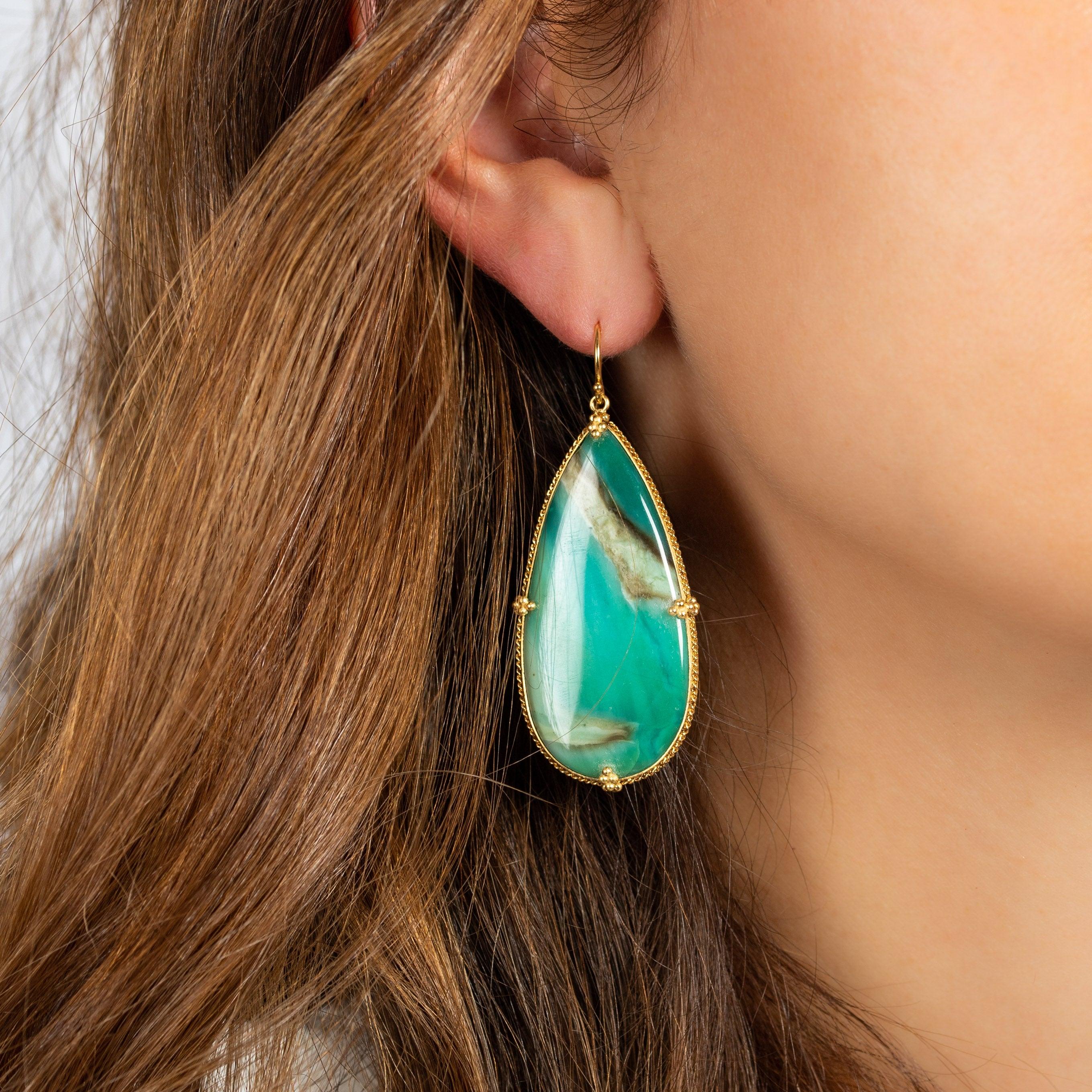 These spectacular earrings feature large and luscious teardrops of Petrified Wood with Blue Opal. It’s a distinctive and unusual material, a captivating stone the color of a tropical lagoon shot through with bands of shadow and light. These
