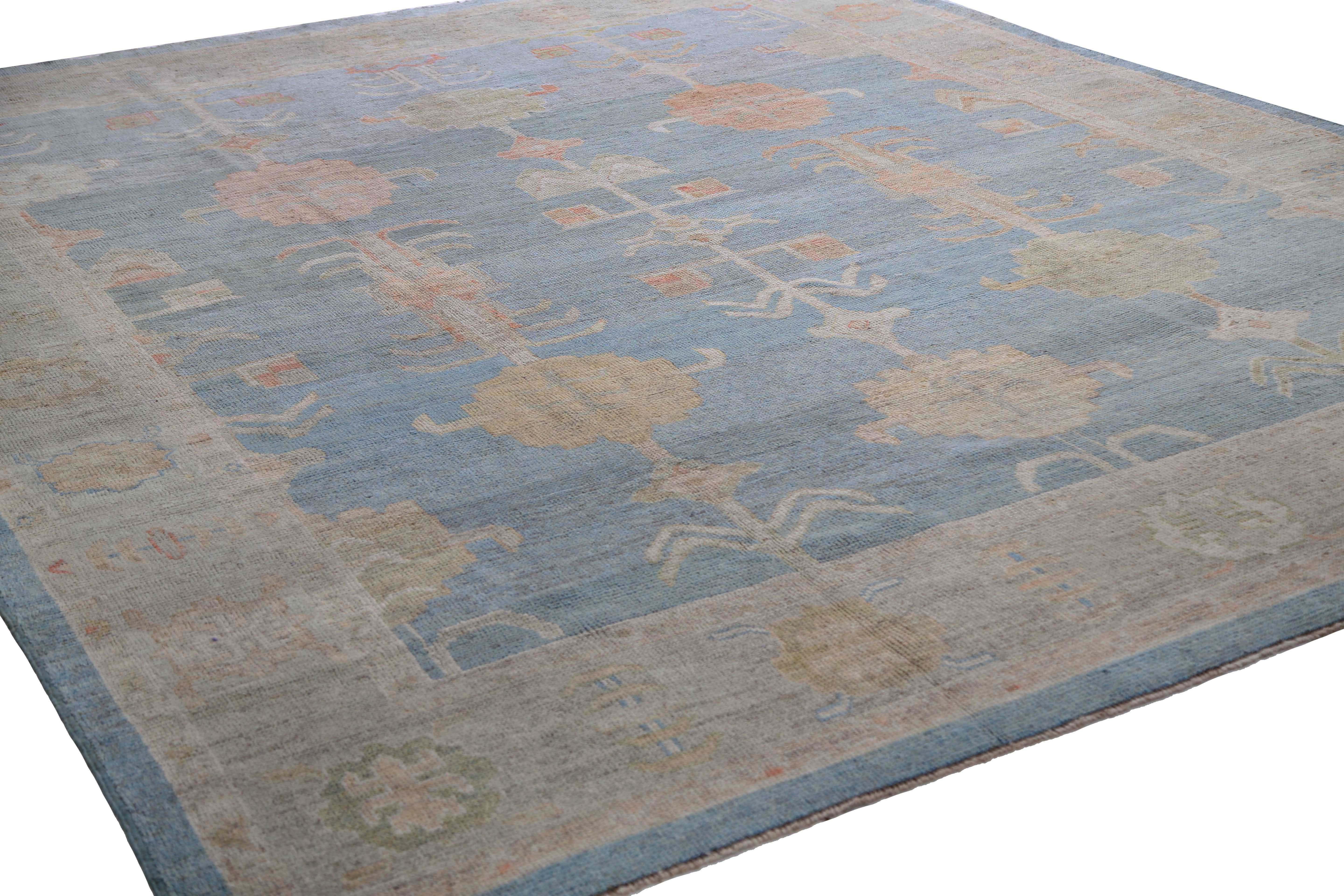 Introducing our stunning Turkish Oushak rug, measuring 10'1'' by 13'0''. This rug boasts a beautiful light blue background that perfectly complements the pops of muted colors such as green, orange, and yellow, making it a perfect addition to any