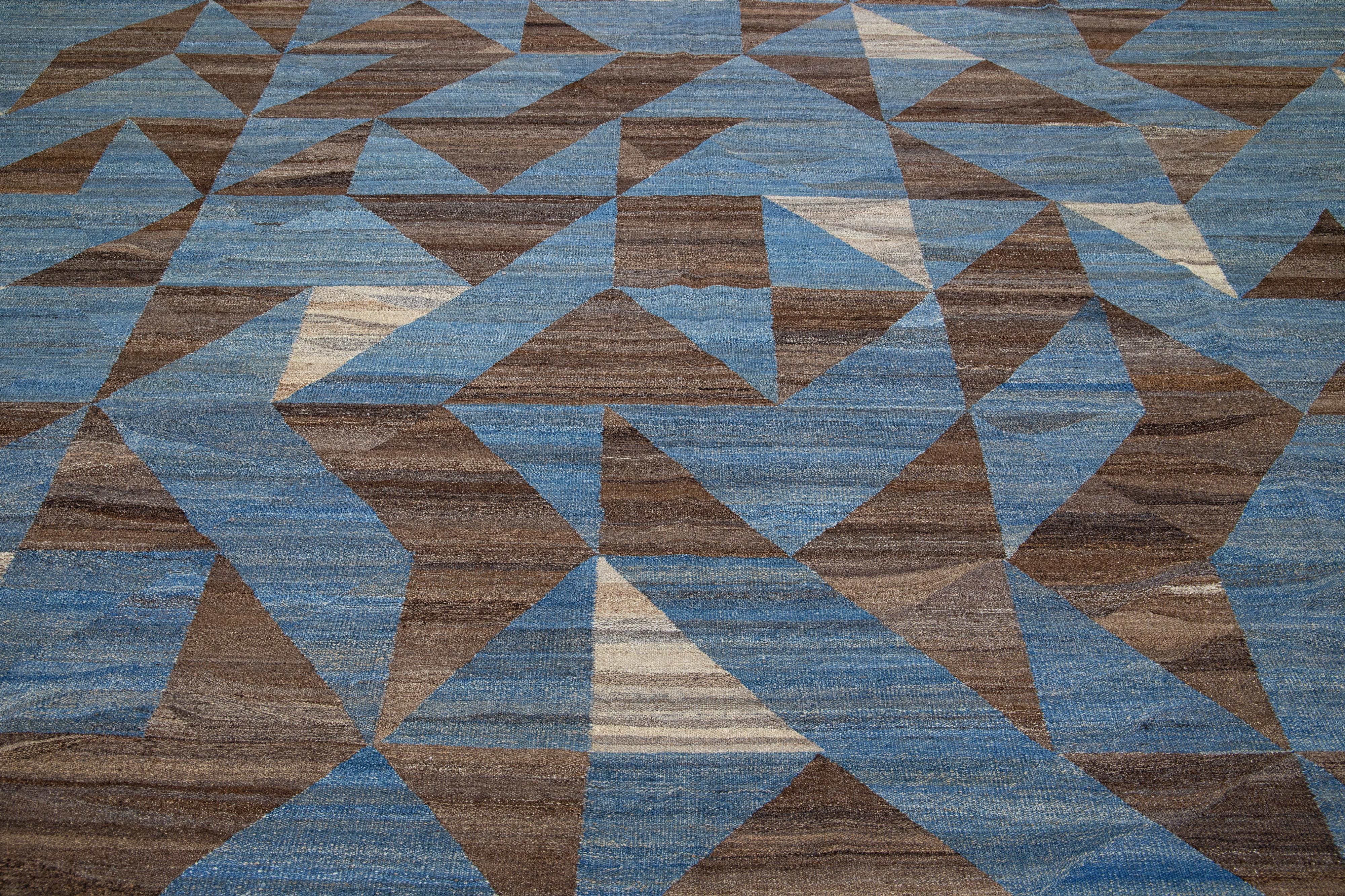 This Deco flatweave wool rug exhibits a captivating blue field with brown and beige accents, creating a contemporary and aesthetically-pleasing abstract design. The natural material of the Deco wool rug is designed for comfort and long-lasting