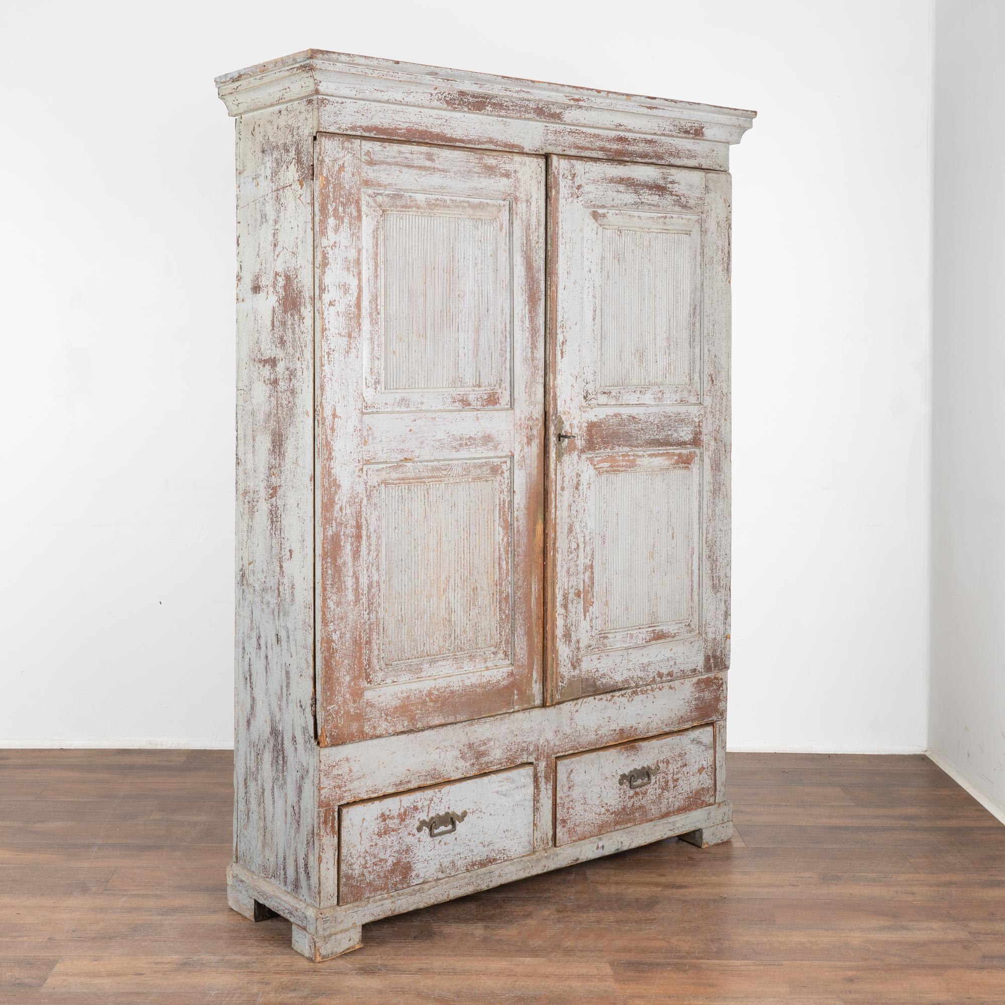 Original blue painted Gustavian armoire or large cupboard from Sweden, early 1800's.
Two cabinet doors with fluted carved panel doors over two functioning drawers, stands over 6.5' tall.
The original blue hand-painted finish has been gently