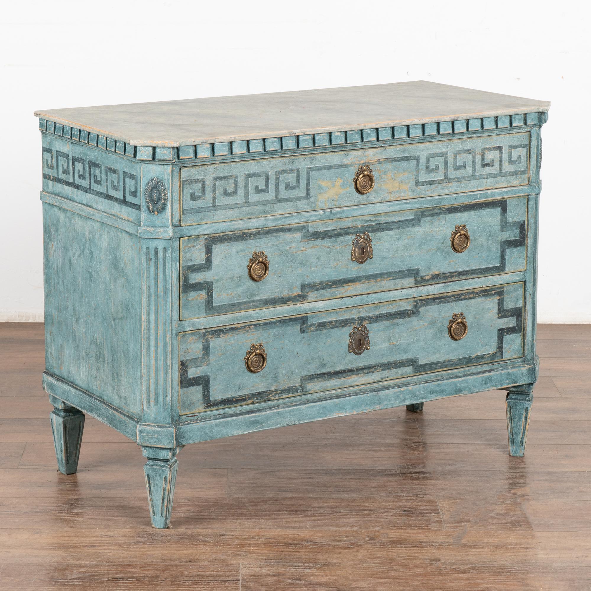 A large decorative Gustavian style pine chest of drawers painted in blue shades.
Contrasting faux marble painted top and dentil moldings.
Three drawers decorated with painted 