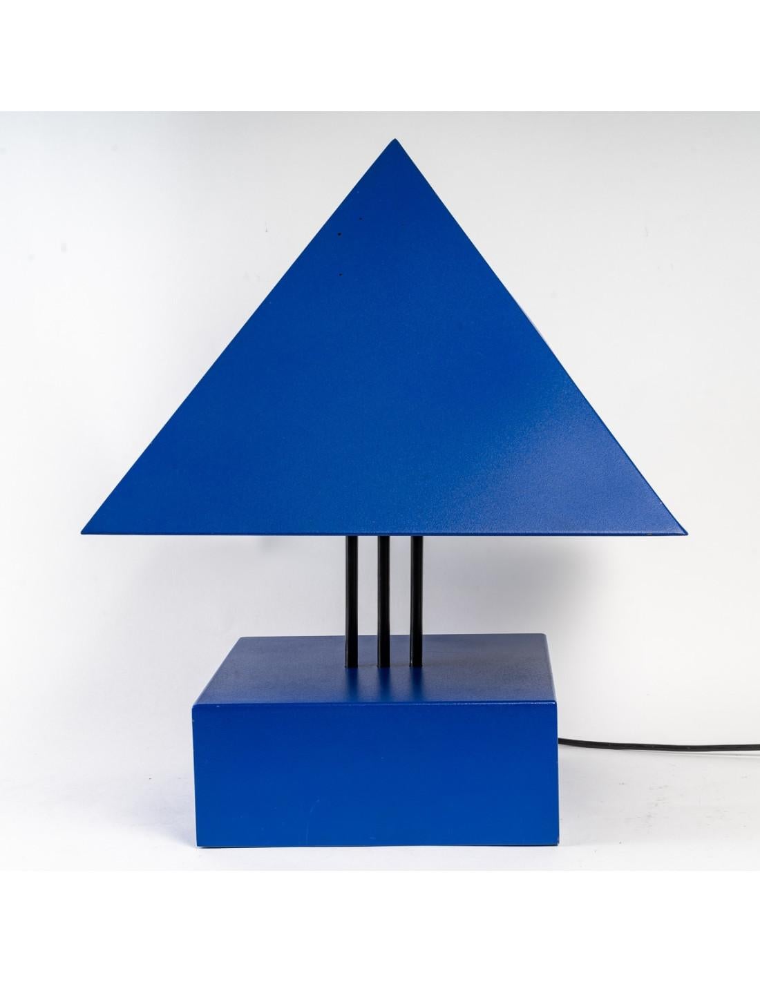Blue painted metal triangle lamp by Alain Letessier, 1987.

Triangle lamp in blue painted metal with its remote control that raises and lowers the metal shade, 2 levels of light, 20th century, designer Alain Letessier (1952)
Measures: H: 52cm, W: 40