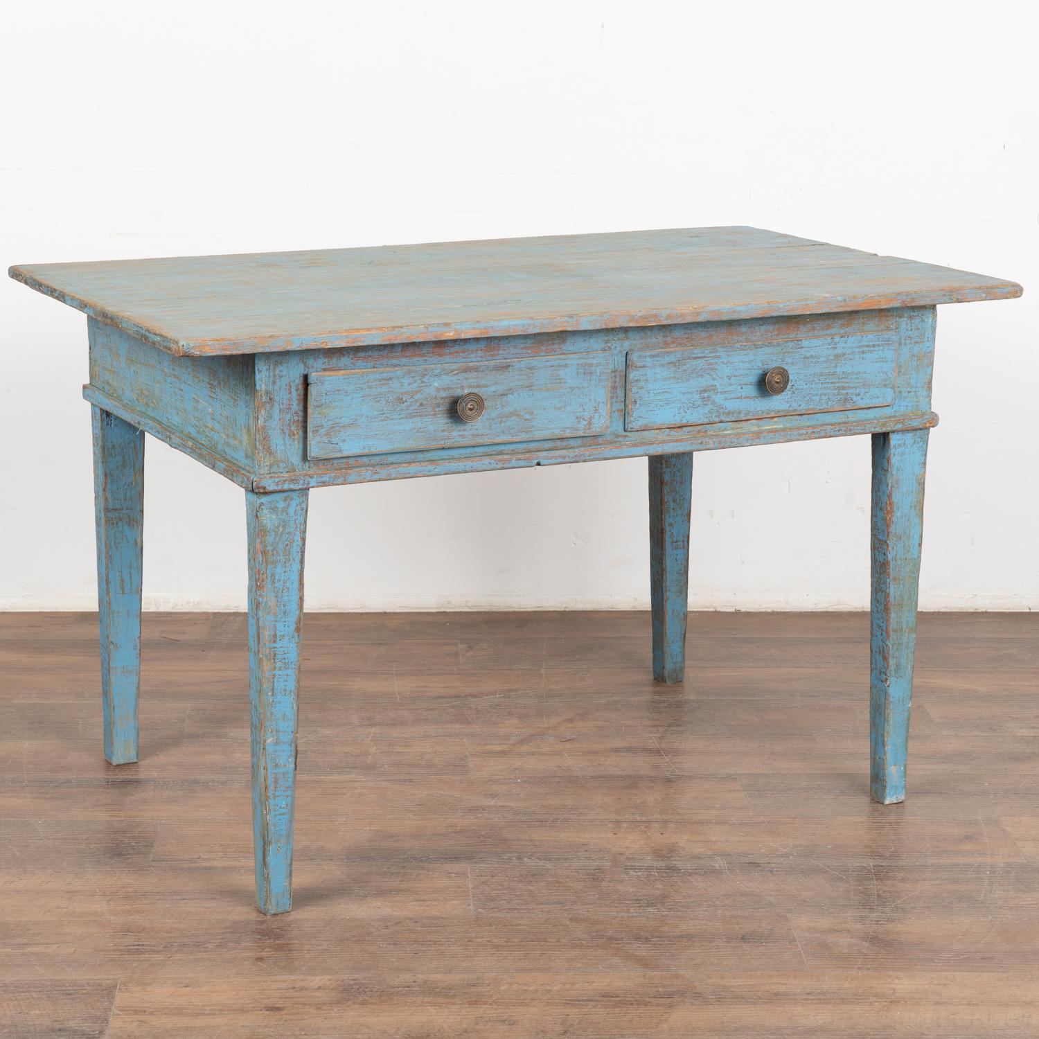 The cheerful blue painted finish has a distressed patina revealing years of use in this small farm table from Sweden.
Notice the two usable drawers with brass pulls that add function and traditional tapered legs.
Whether this is used as a kitchen