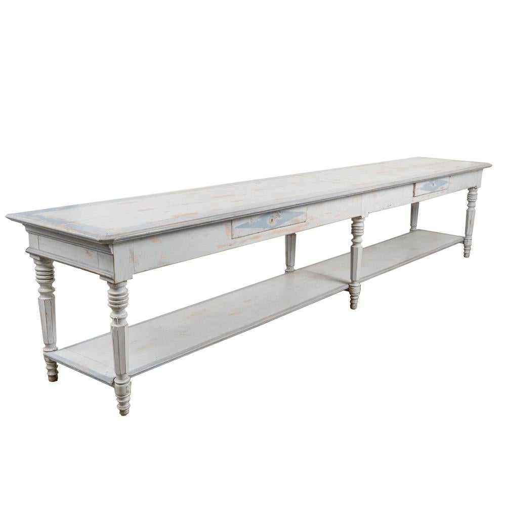 An incredible find, this impressive long narrow refectory table from France is painted light blue (with gray undertones) and accented with darker blue trim around edges and diamonds on two drawers.
The lower shelf and turned legs add to the