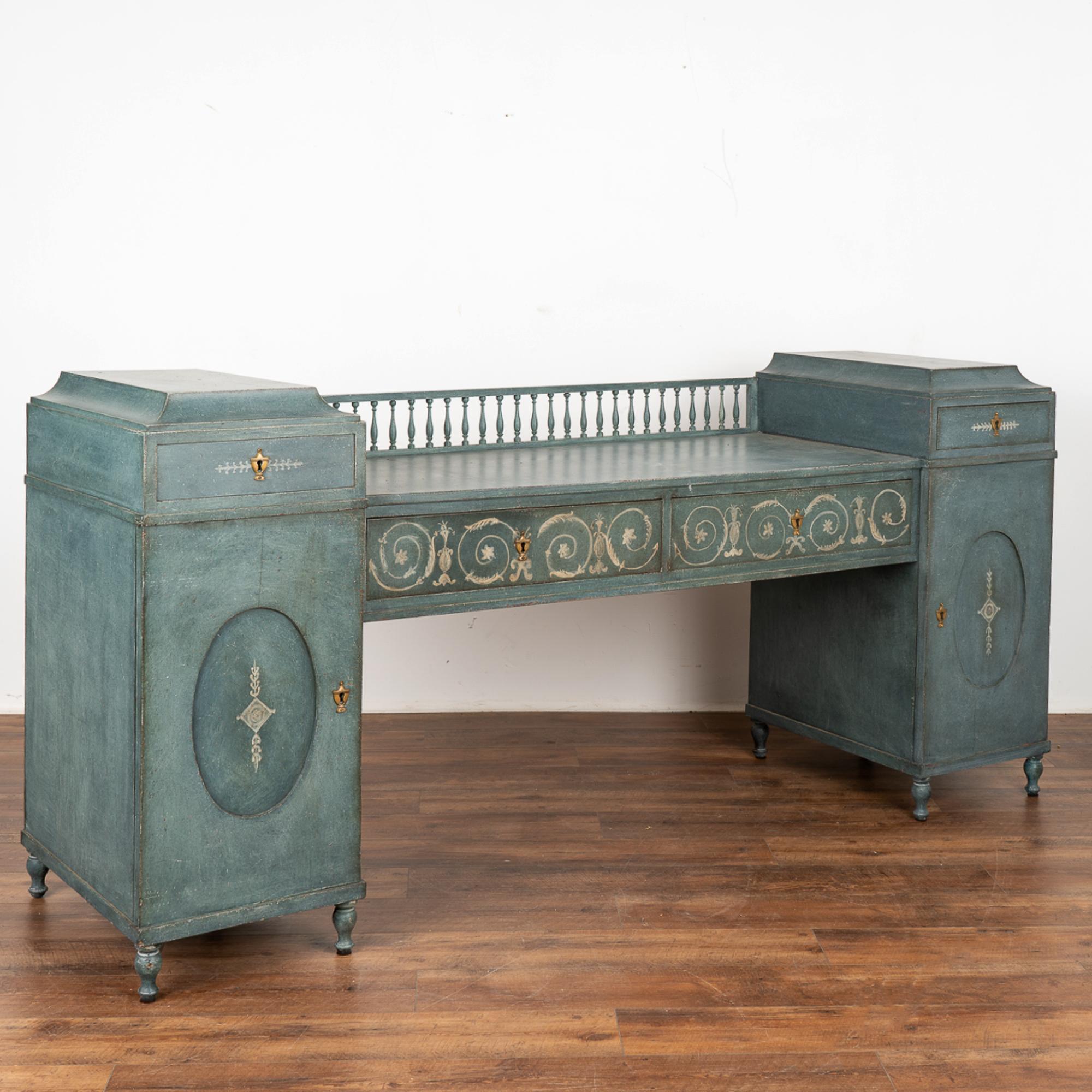 Elegant English sideboard with spindle back which will serve well as a buffet or console.
The later applied old layered blue painted finish with white flourishes adds to the sophisticated appeal of this server.
See photos with all the doors and