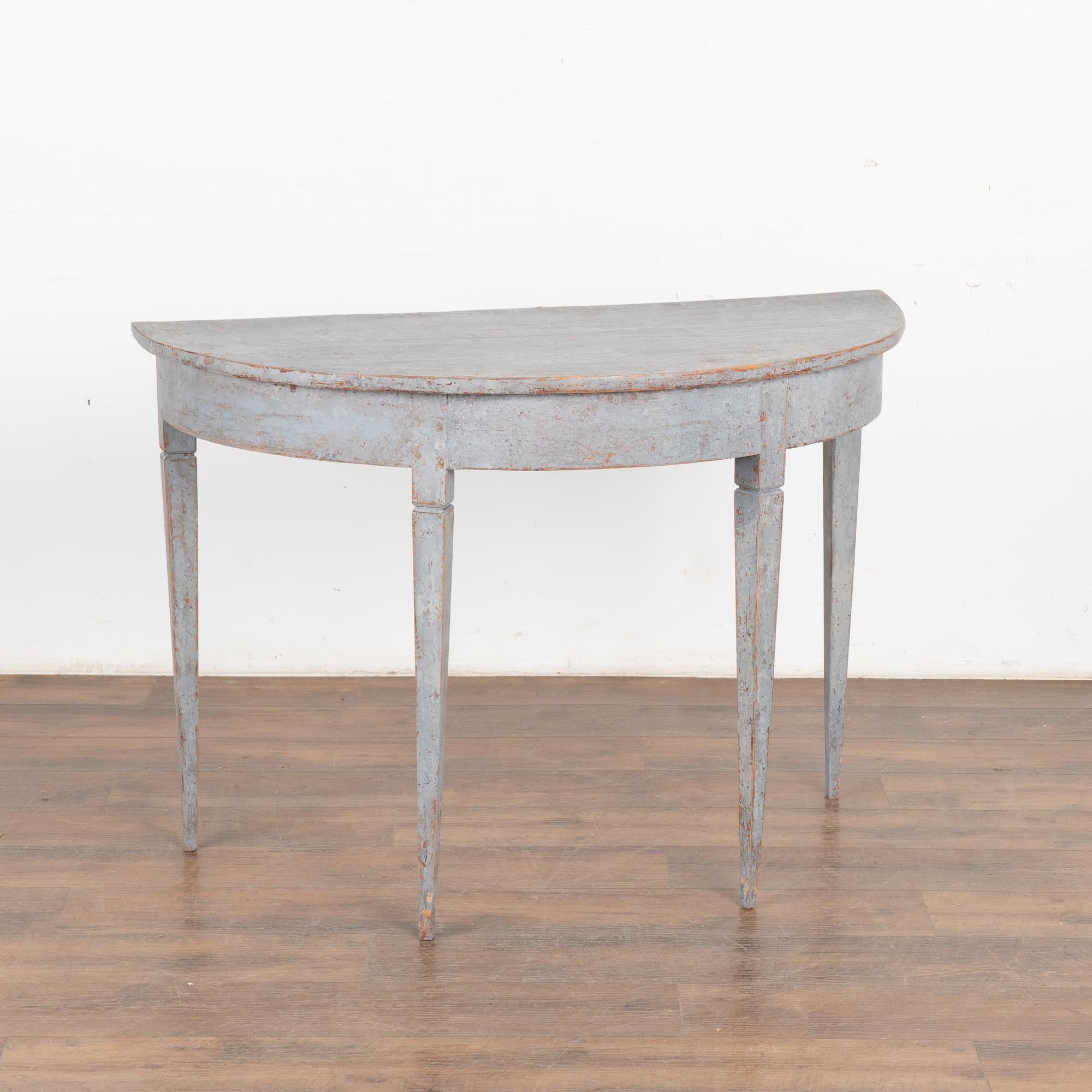 Single pine demi-lune side table with simple Swedish country design and gently tapered legs.
Newer professionally applied pale blue painted finish with gray undertones, slightly distressed to fit age and grace of this console.
Restored, strong and