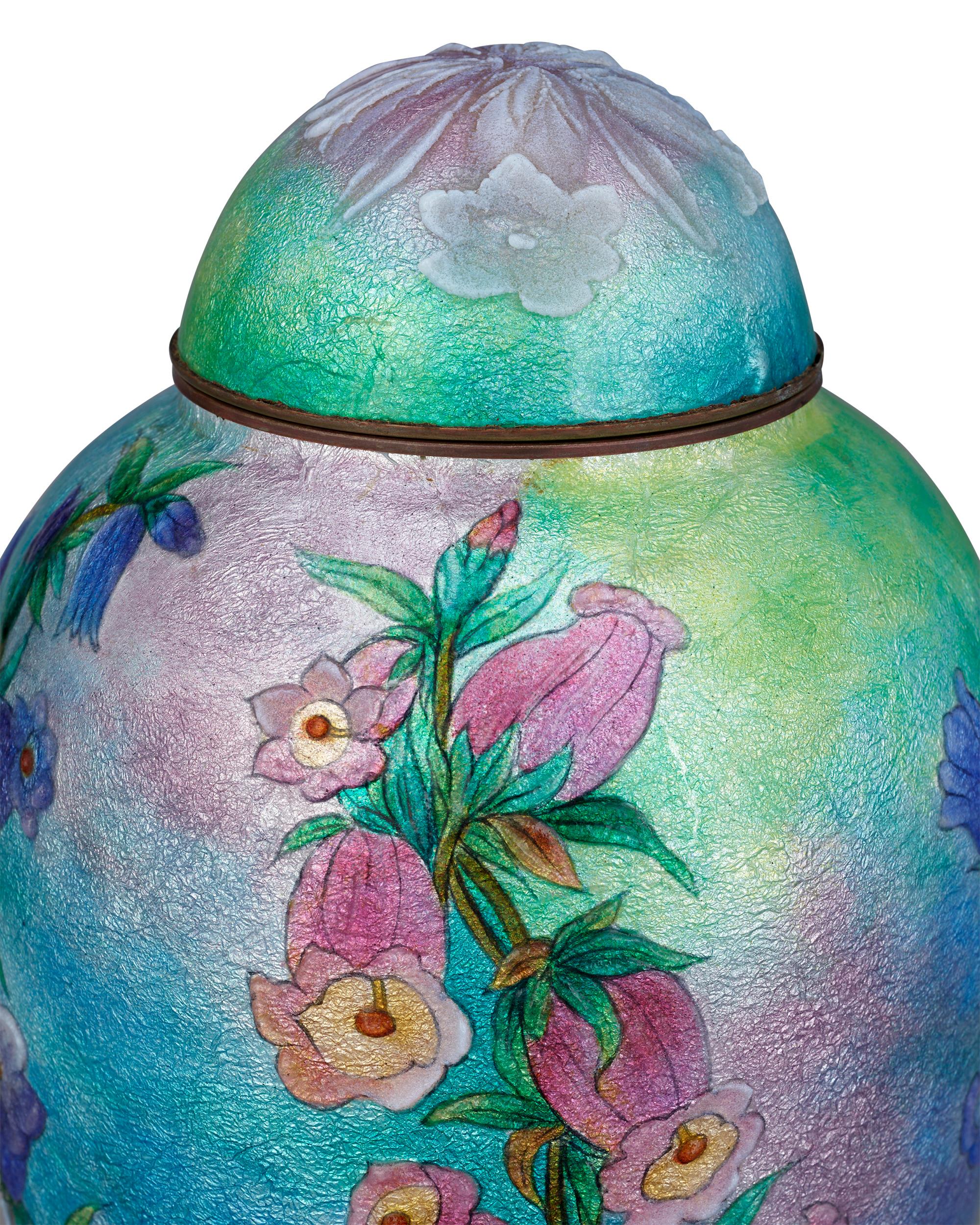 De délicates fleurs roses semblent jaillir de ce vase bleu émaillé de Limoges de Camille Fauré, décoré de vibrants motifs de mufliers. Des couches et des couches d'émail aux teintes vives et aux lignes gravées de manière experte ont été appliquées