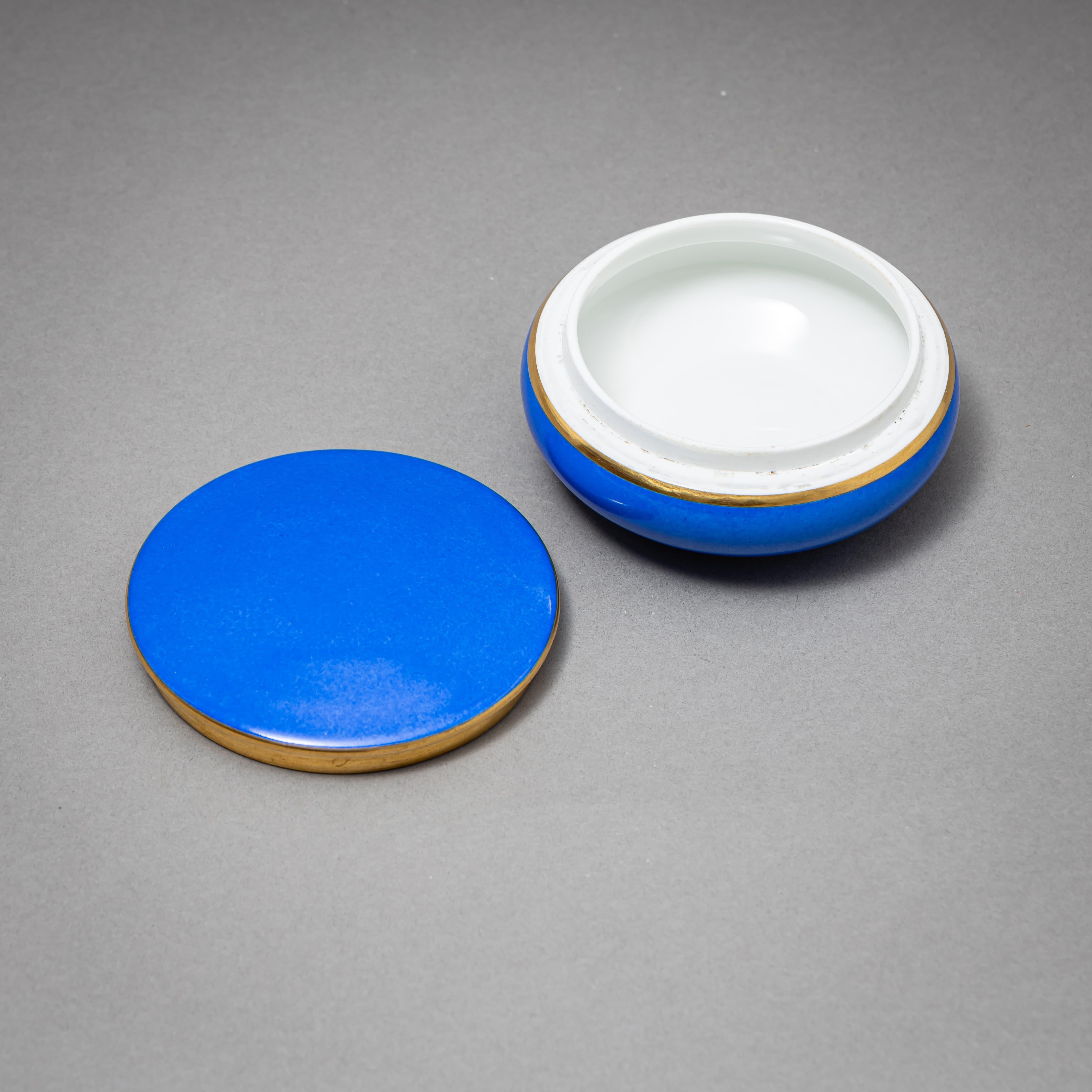 Small round porcelain box with matching lid and gilt-edged rim. The surface is finished in a vibrant blue glaze. Marked on the underside with the green underglaze mark of the Nymphenburg porcelain manufactory.