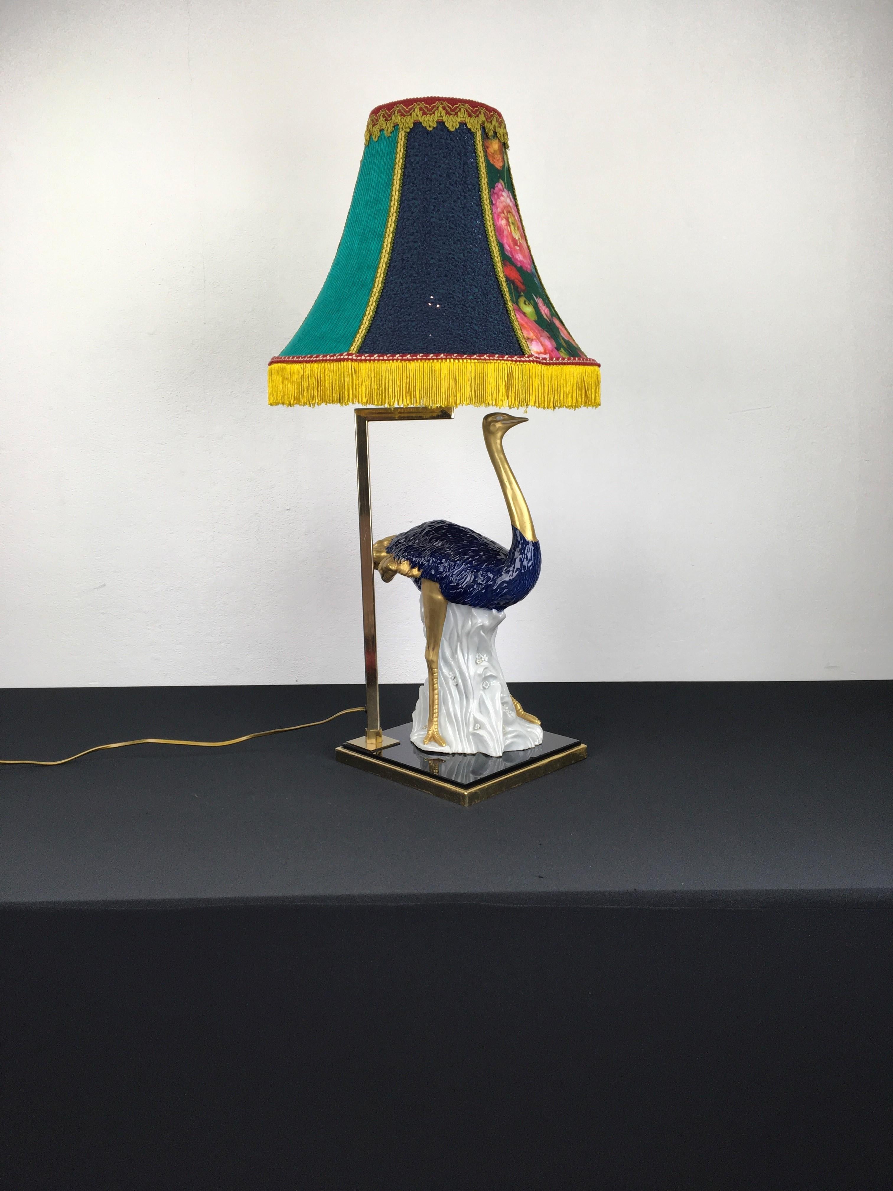 Blaue Porzellan-Tischlampe in Form eines Straußenvogels. 
Diese außergewöhnliche und stilvolle Vintage-Tischlampe hat einen kobaltblauen mit Gold bemalten Porzellanstrauß, der 
montiert auf einem kobaltfarbenen Glas mit Facettenschliff. Der Vogel