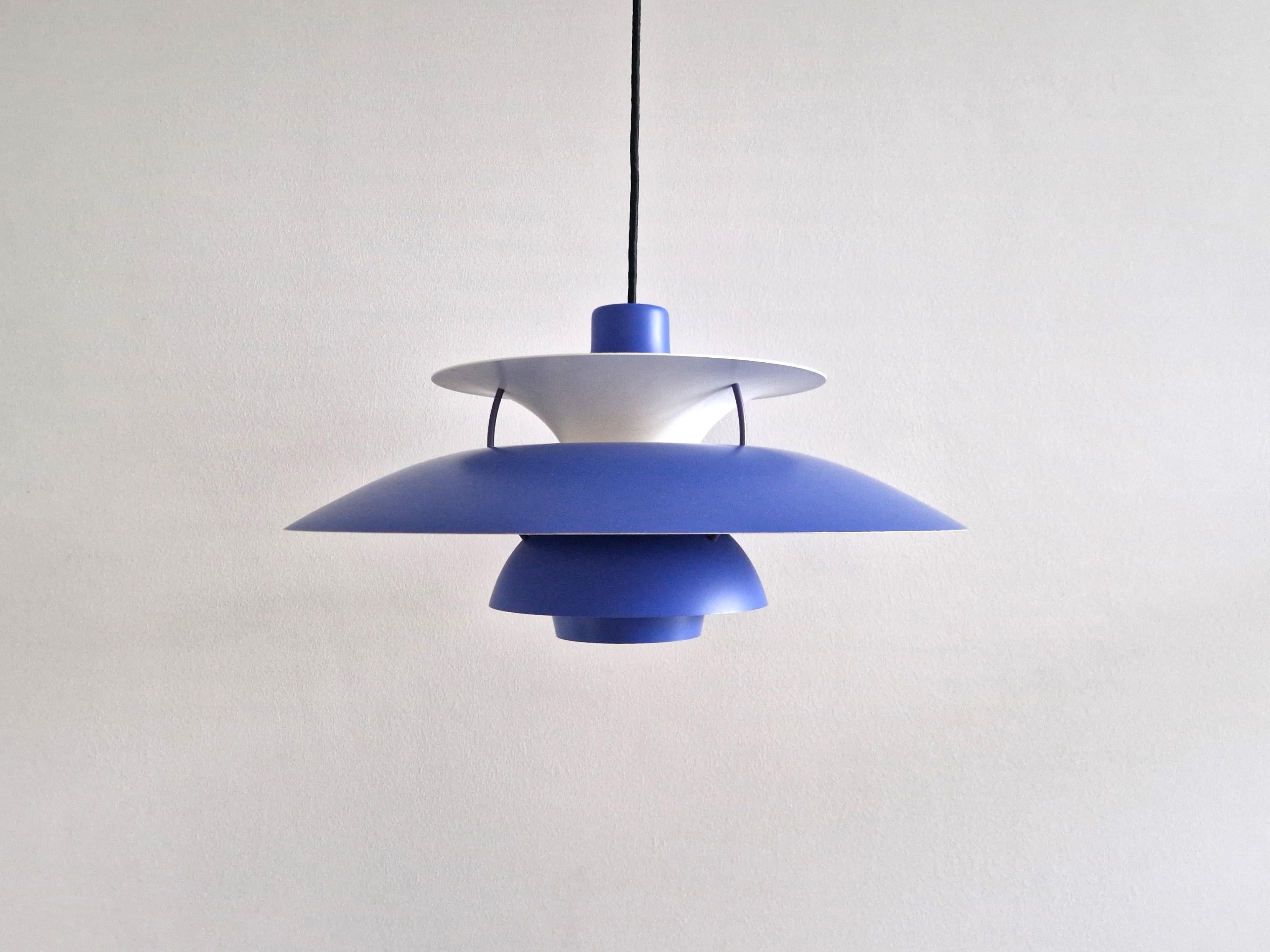 The timeless model PH5 pendant lamp was designed by Poul Henningsen for Louis Poulsen in 1956. This lamp has a blue purple shade with a red circle plate for the socket and top shade. The label show that this specific light is of later production