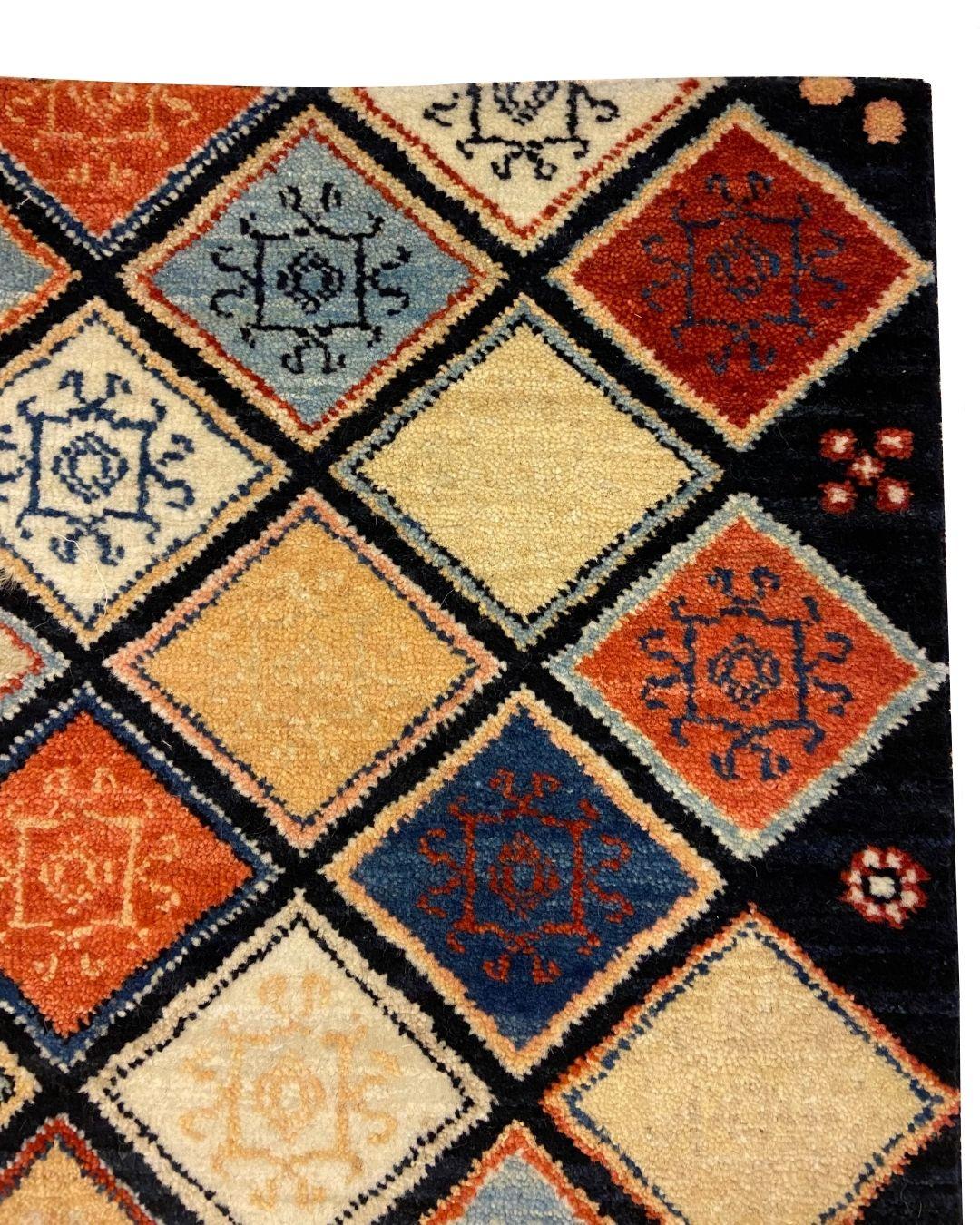 Ce tapis persan bleu, rouge, corail, crème et or à motifs géométriques, de taille 2' x 3', est une vibrante vitrine de l'art d'Orley Shabahang et de son souci du détail. Le tapis présente une disposition complexe de motifs en forme de diamant,