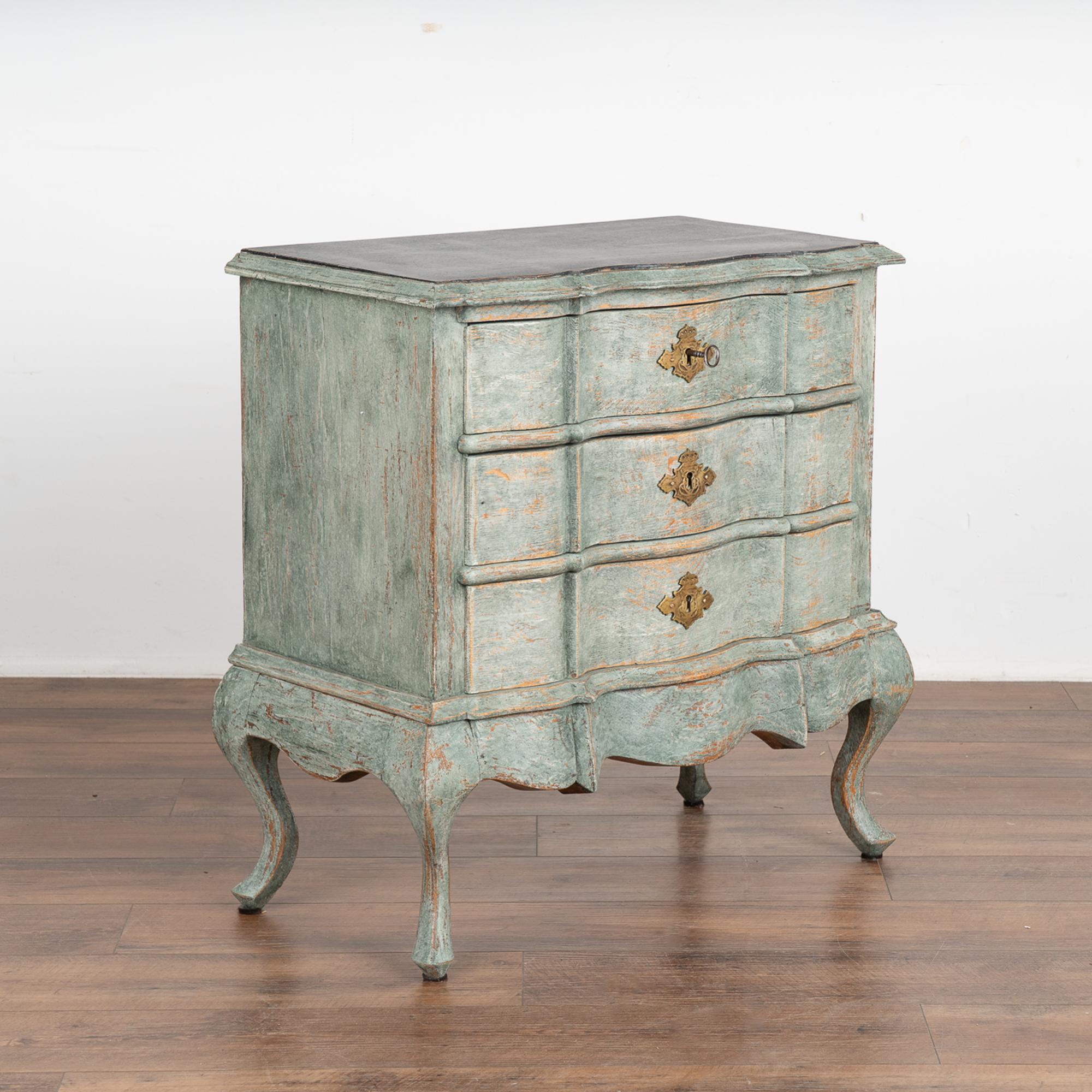 A small oak rococo chest of three drawers with brass key escutcheons. The scalloped edge of the top is carried down through the 3 drawer fronts and bottom apron resulting in an elegant, bow front case all resting on four cabriole legs.
The newer,
