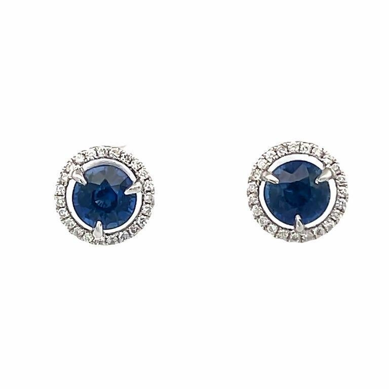 This pair of earrings are made of two round blue sapphire stones in the center with a total weight of 2.15CT carats selected for their color and beauty. These elegant blue sapphire earrings are made also with a single row of round white diamonds