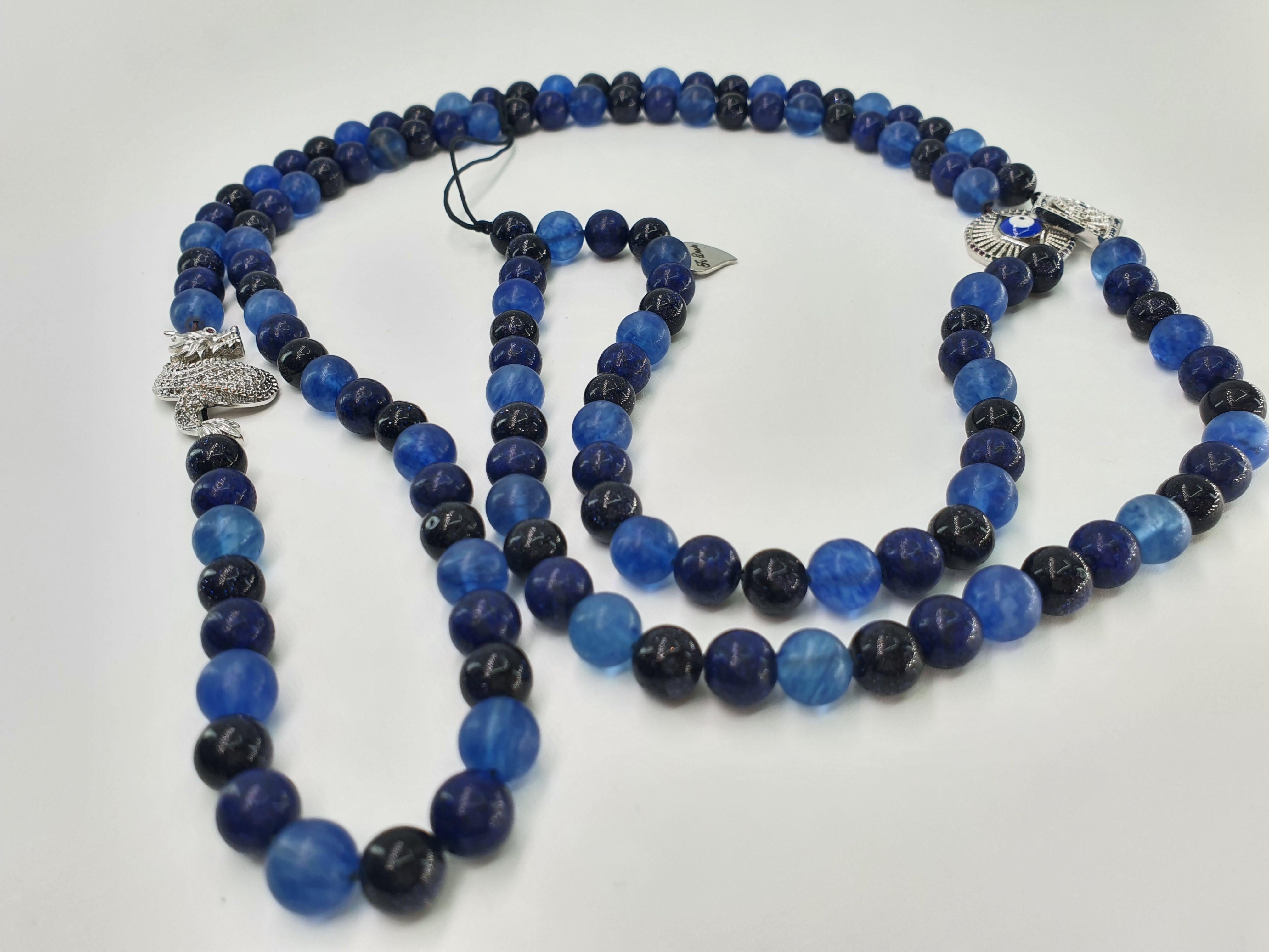 This beautiful fashion blue sand stone, lapis lazuli and watermelon blue beads with 3charms: dragon, square evil eye and rainbow evil eye can be used as an accessory for a phone, hand bag, like a necklace or body accessory.
The strap is carefully