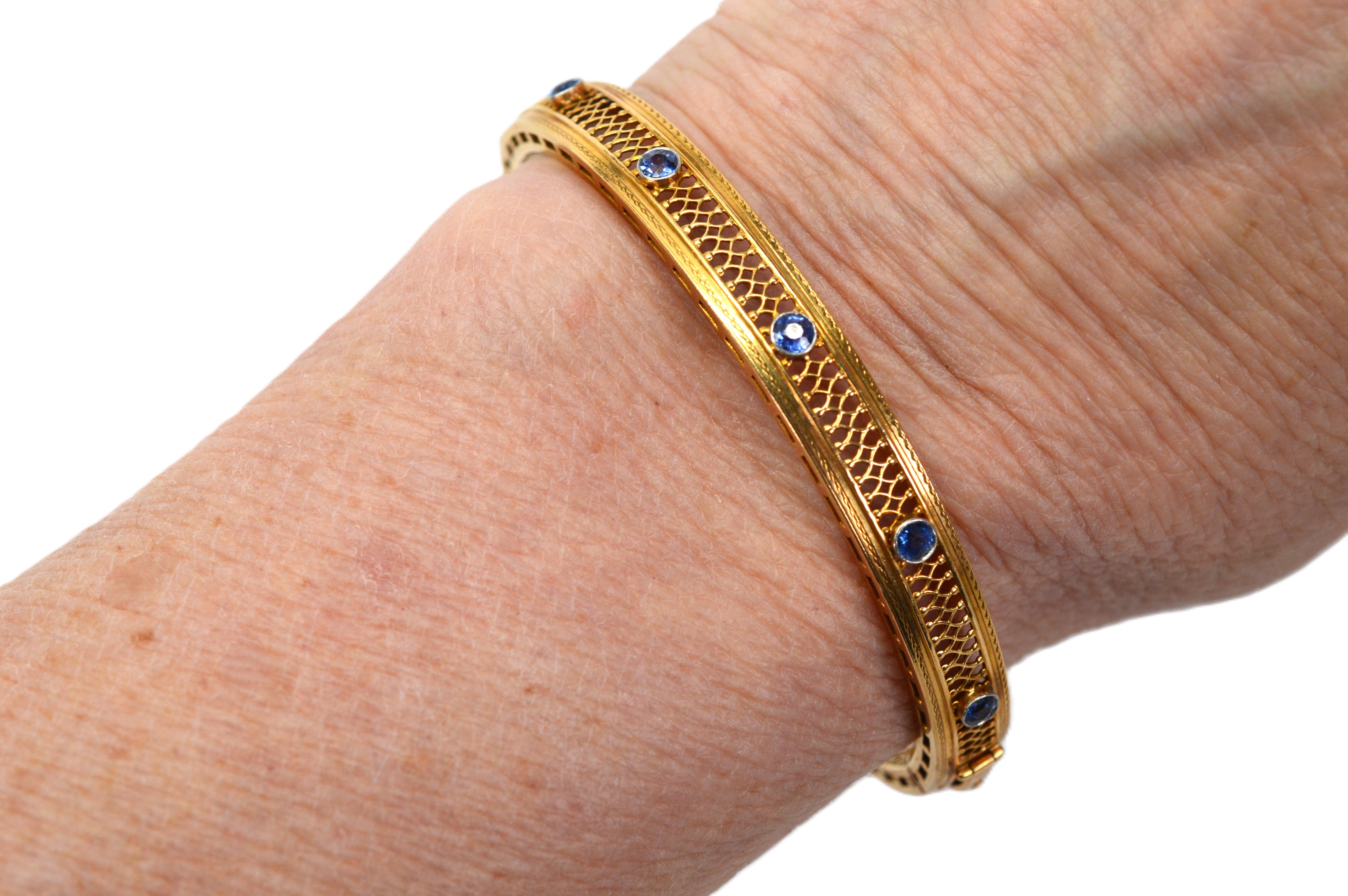 Vibranti zaffiri blu tagliati a mano vestono con eleganza la parte anteriore di questo bracciale bangle vintage in oro giallo 14 carati finemente realizzato da William C. Boyajian. L'intricata filigrana d'oro a motivo aperto conferisce un aspetto