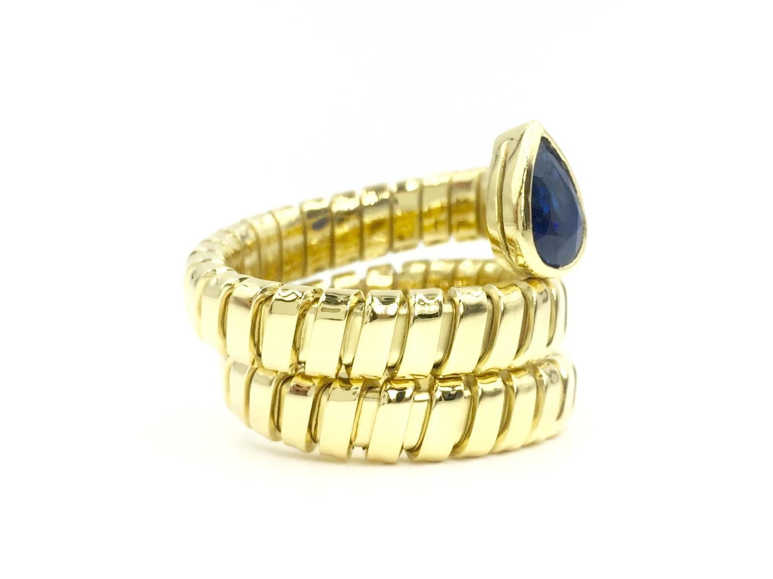 Italian made high polished 18 karat yellow gold flexible wrap ring featuring a beautiful 1.20 carat pear shape blue sapphire. Blue sapphire has a vibrant medium royal blue color.
Width of ring measures 19mm from point of pear to bottom of ring.
