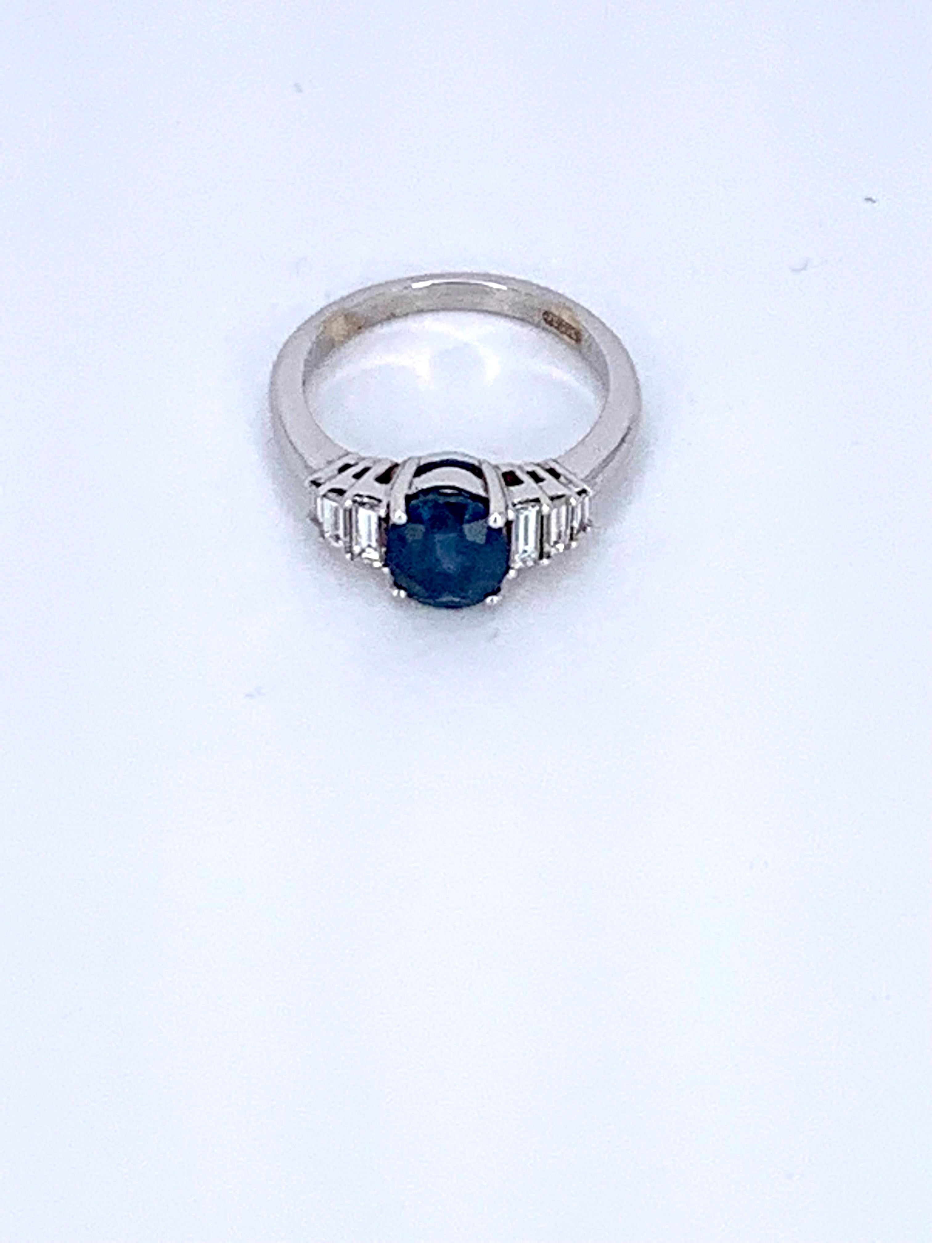 This exquisite round Blue Sapphire 1.93 carat with 0.43 Carats of White Diamond baguette either side, is a beautiful cocktail ring set in 18Kt white Gold.

The circular Sapphire is dressed with Diamond baguettes on either side of the face of the
