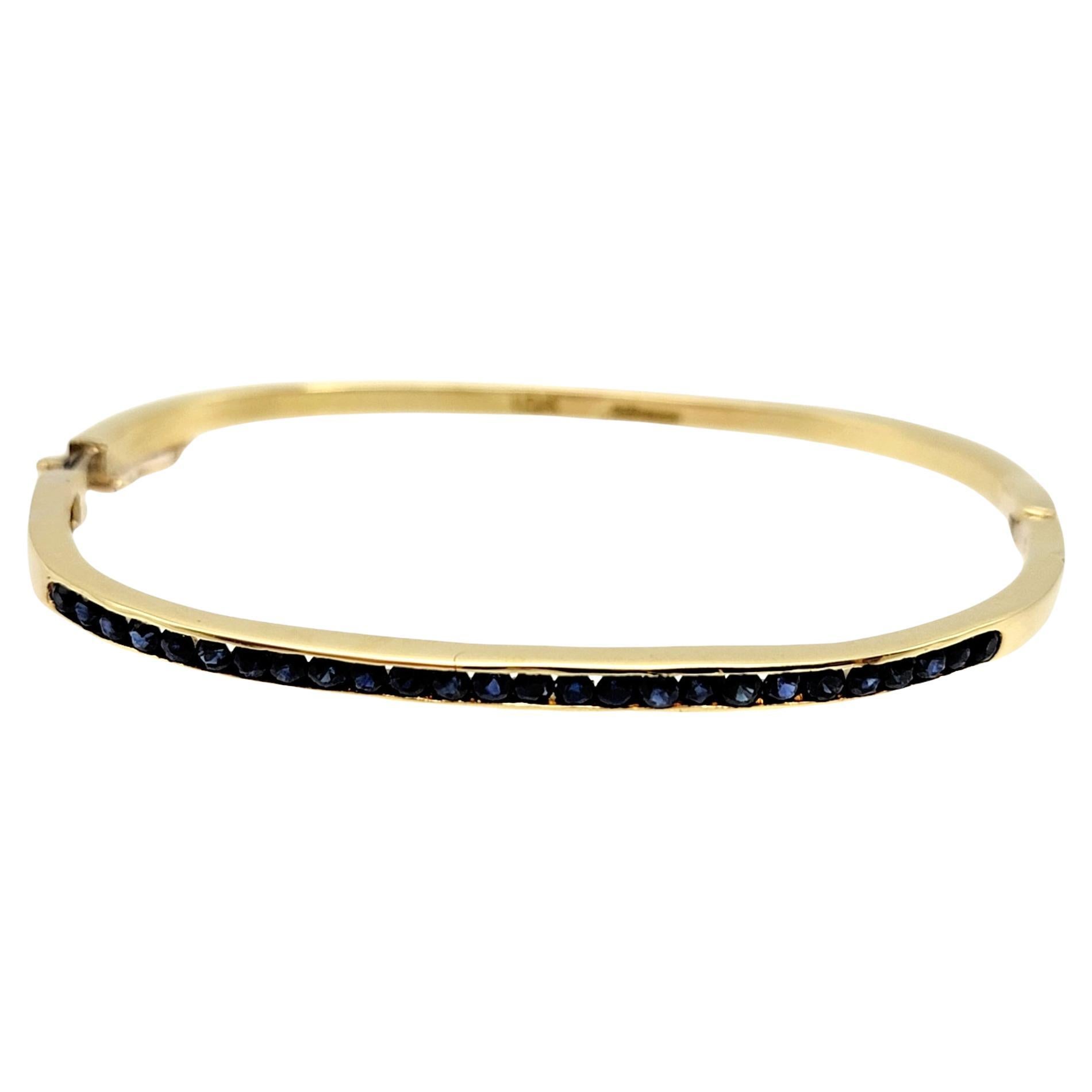 Delicate yellow gold bangle bracelet accented with a single elegant row of round channel set sapphires in a deep blue hue. 

Metal: 18K Yellow Gold
Natural Sapphires: 1.04 ctw
Sapphire cut: Round Brilliant
Sapphire color: Blue
Sapphire clarity: