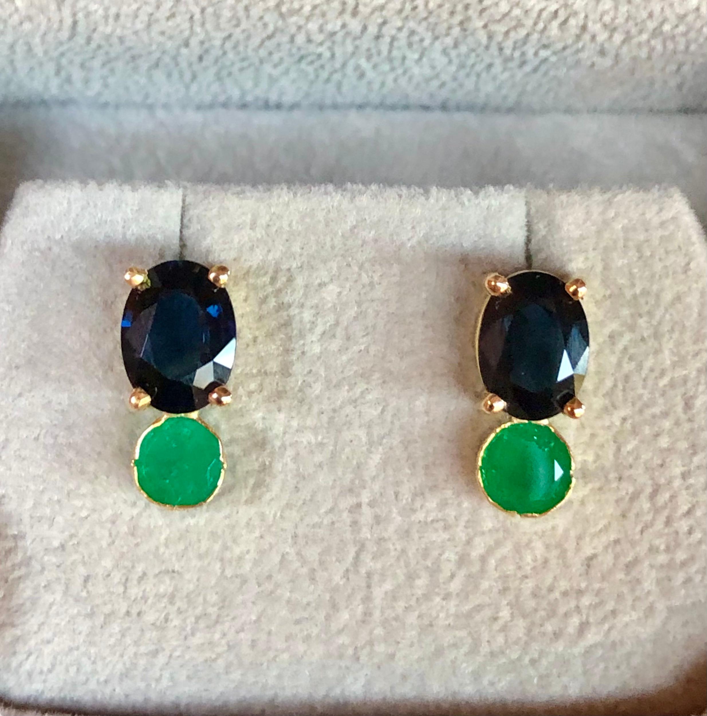 Stunning one-of-a-kind 3.85 carat stud earrings featuring two blue oval royal blue sapphires, and round cut Colombian Emeralds. Set in 18K yellow gold.  
Sapphires weigh 2.65 carats, VS in clarity 
Colombian emeralds 1.20 caras, SI in