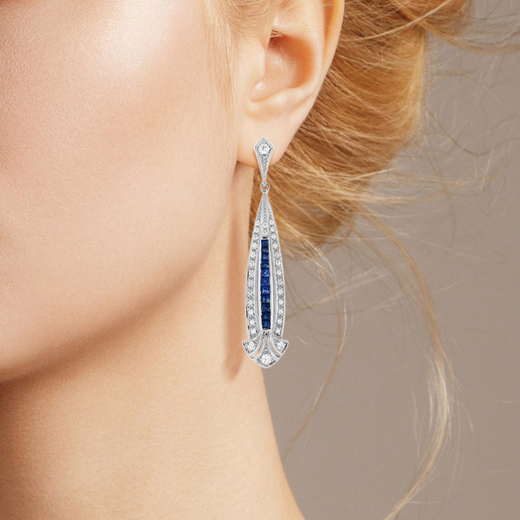 Une fabuleuse paire de boucles d'oreilles en saphir bleu et diamant d'inspiration Art Déco. Ces magnifiques boucles d'oreilles sont composées d'un long saphir bleu de taille française et d'un diamant en forme de flèche, suspendus à un diamant rond