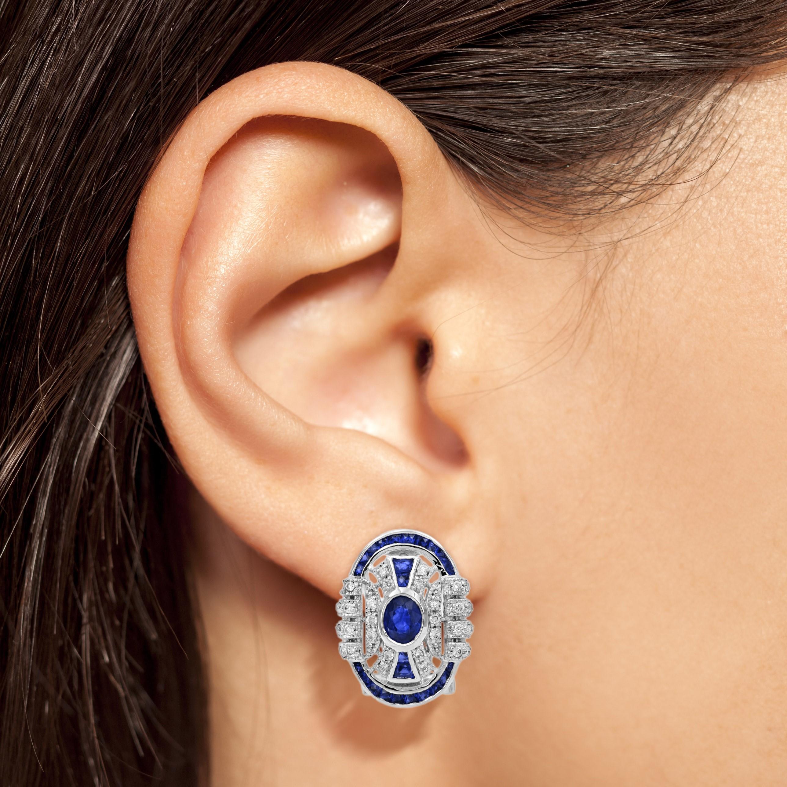An Art Deco inspired pair of earrings that draws all the attention to the oval shaped blue sapphires placed in the middle. Adorned with approx. 0.41 carats diamonds (total) and French cut blue sapphire borders, this gorgeous earrings sparkle with