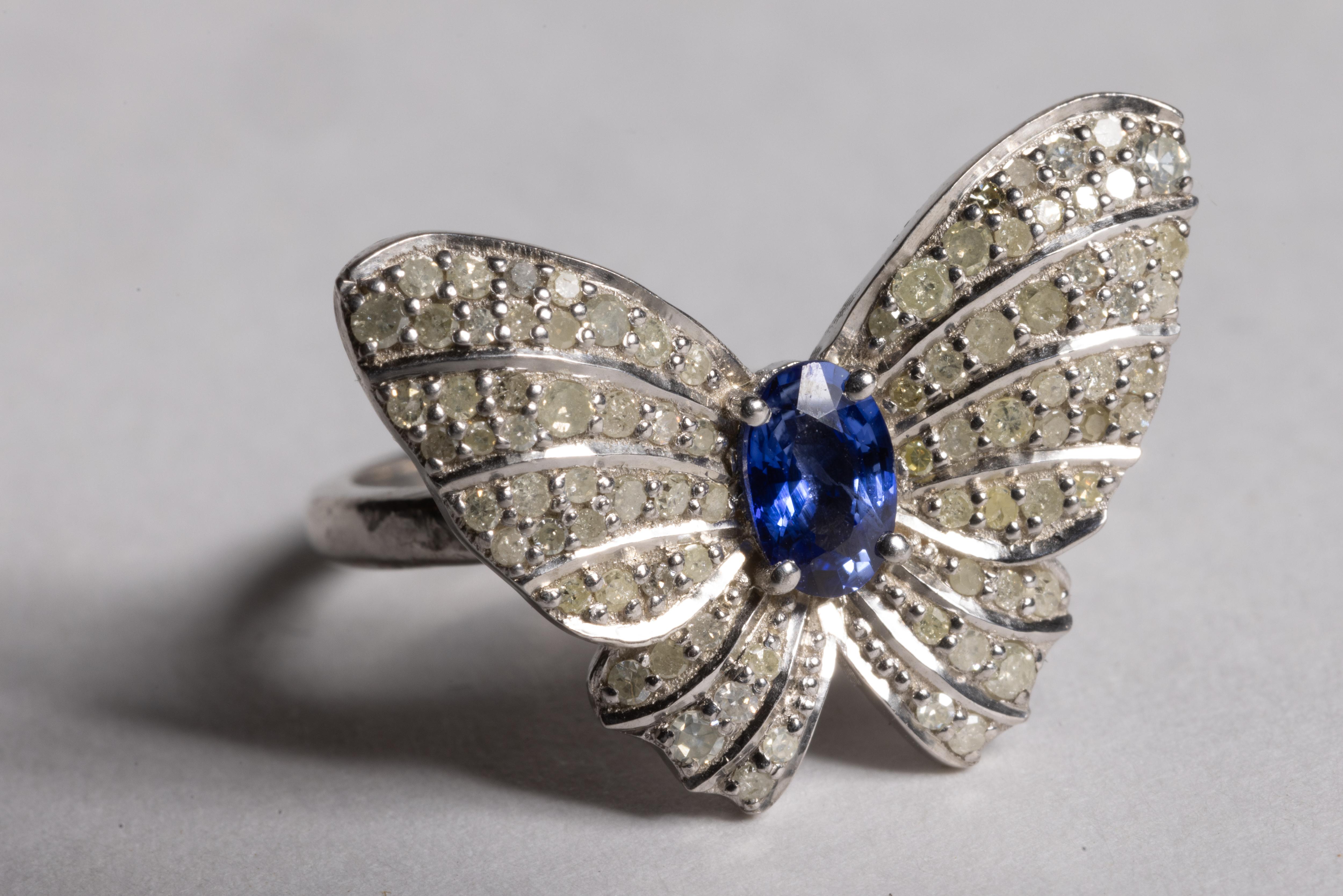 A fun butterfly motif ring featuring a center, round faceted blue sapphire and round, brilliant cut diamonds comprising the wings.  Set in  sterling silver.  Blue sapphire is .55 carats and diamonds total .65 carats.  Ring size is 6.75.

The fine