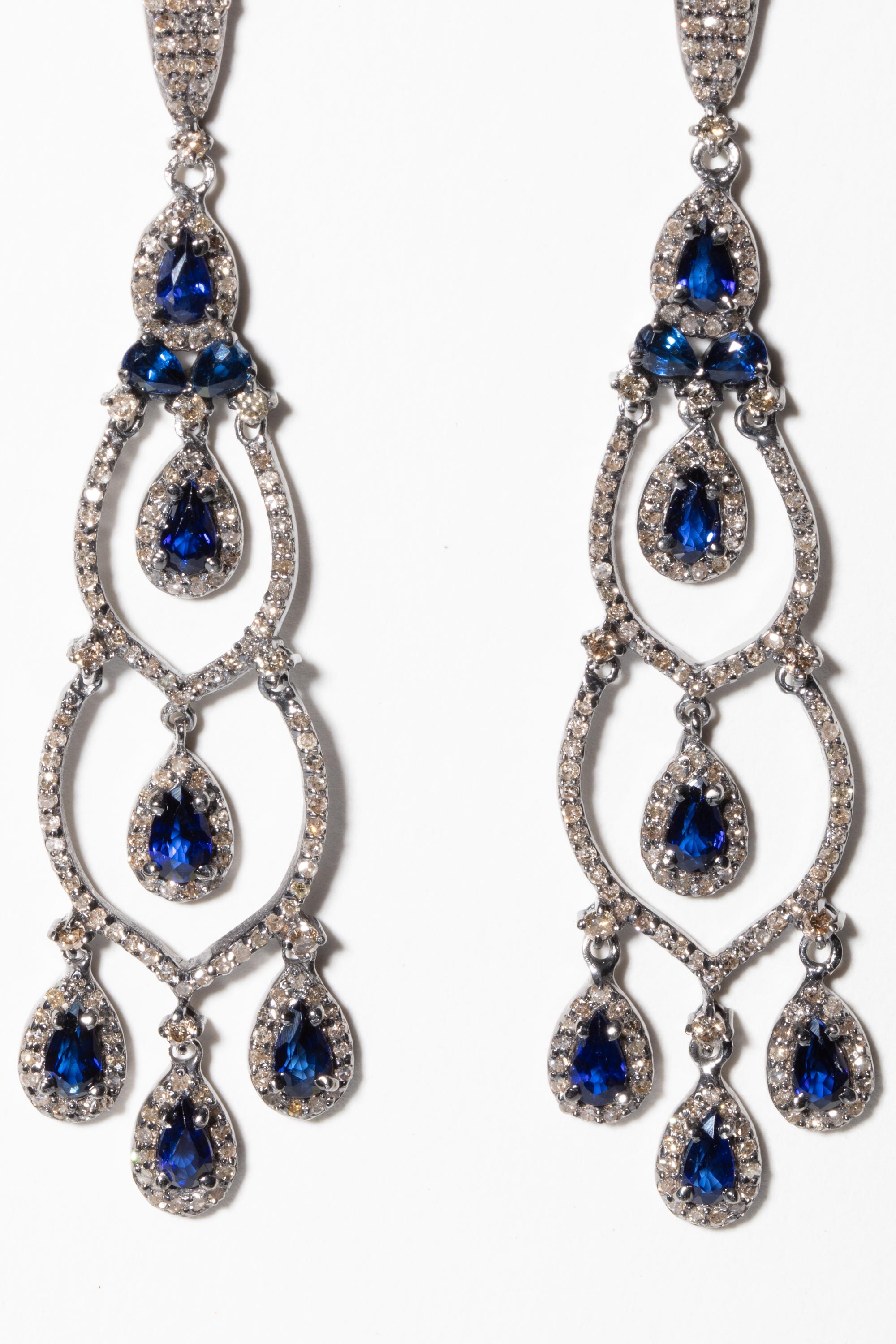 Pair of pear-shaped, faceted blue sapphire chandelier earrings bordered in pave`-set diamonds and on earring post as well.  Set in sterling silver with an 18K gold post for pierced ears.  Carat weight of diamonds is 2.29, sapphires are 3.07 carats.
