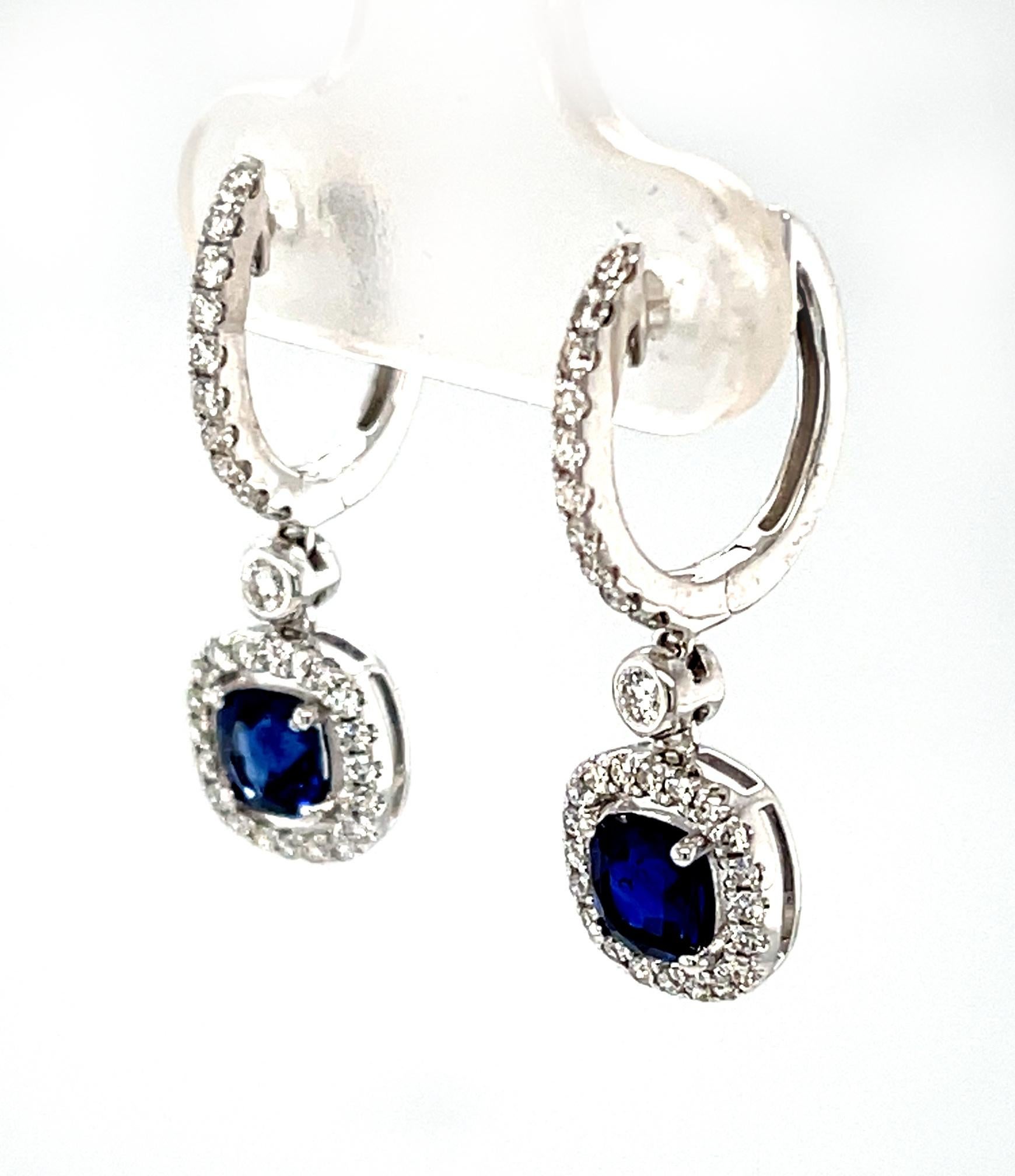 These elegant sapphire and diamond earrings feature a matched pair of beautiful, gem blue sapphires! 18k white gold floating halos create a lovely frame around the rich, royal blue cushions and are set with brilliant, sparkling diamonds. Each drop
