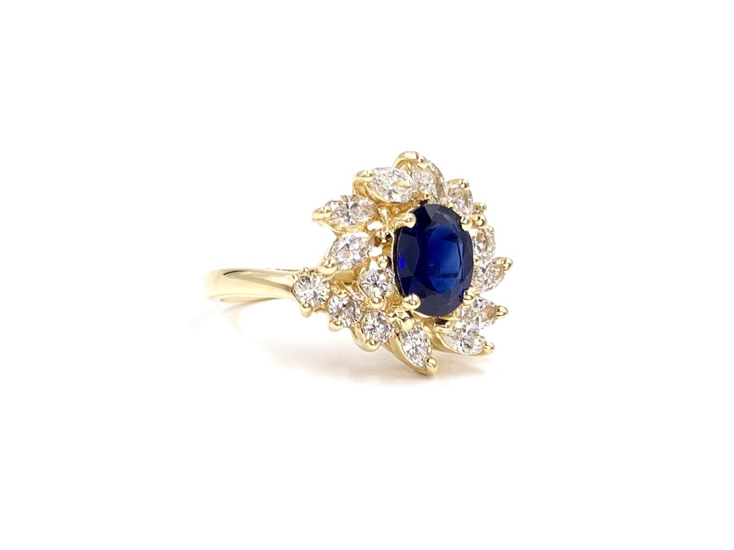 A truly exquisite find. This 14 karat yellow gold sparkling piece features an oval deep blue sapphire surrounded by high quality marquise and round brilliant white diamonds. Blue sapphire measures 8mm x 6.3mm at approximately 1.25 carats.