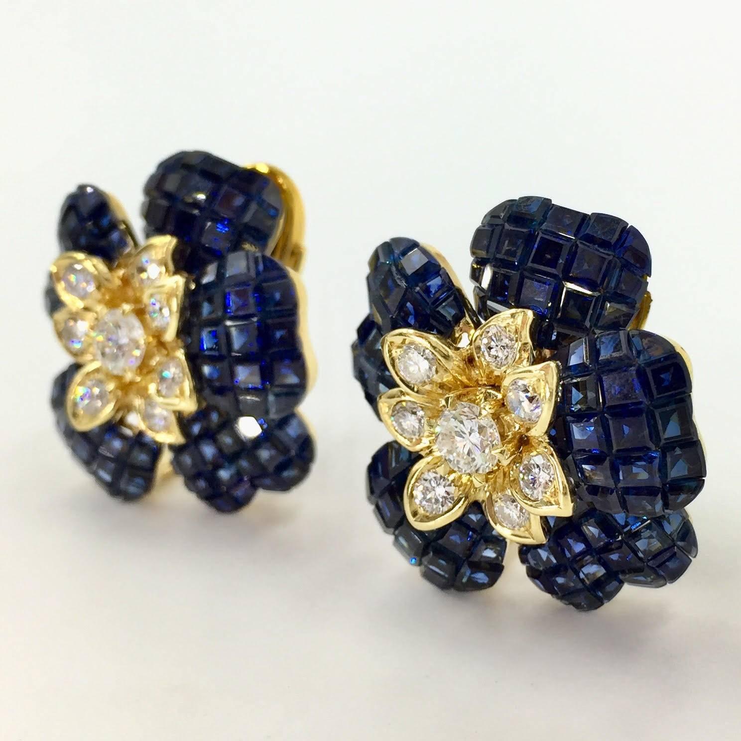 Unique flower earrings with exceptional design. Invisibly set vibrant blue sapphire petals surround a beautiful diamond and yellow gold center. Sapphires are of excellent shade of royal blue - not at all dark or black looking. Diamonds are of very