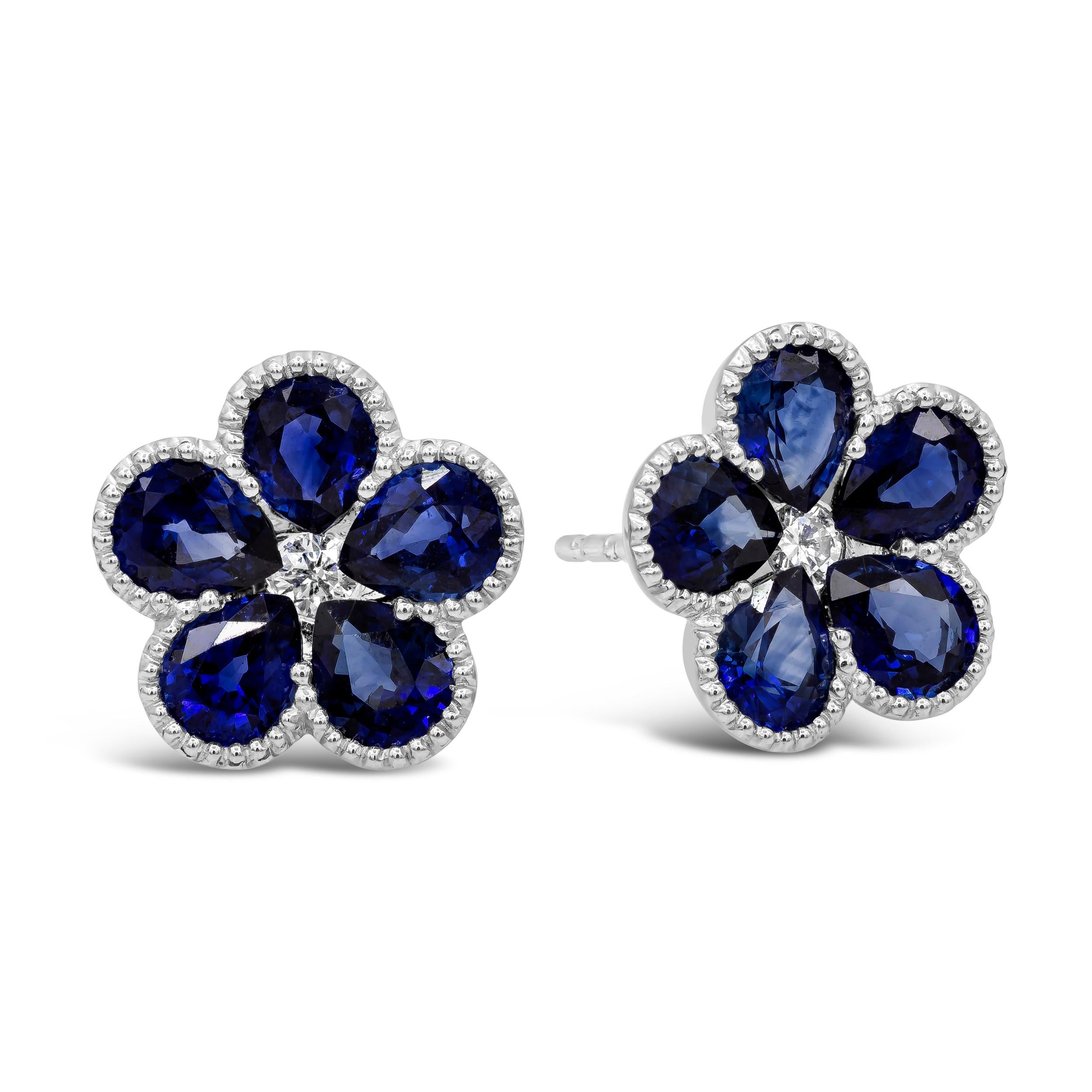 A fashionable pair of earrings featuring pear shape blue sapphires set in a flower. Each flower is set with a round brilliant diamond center, and finished with millegrain edges. Sapphires weigh 3.53 carats total. Diamonds weigh 0.11 carats total.