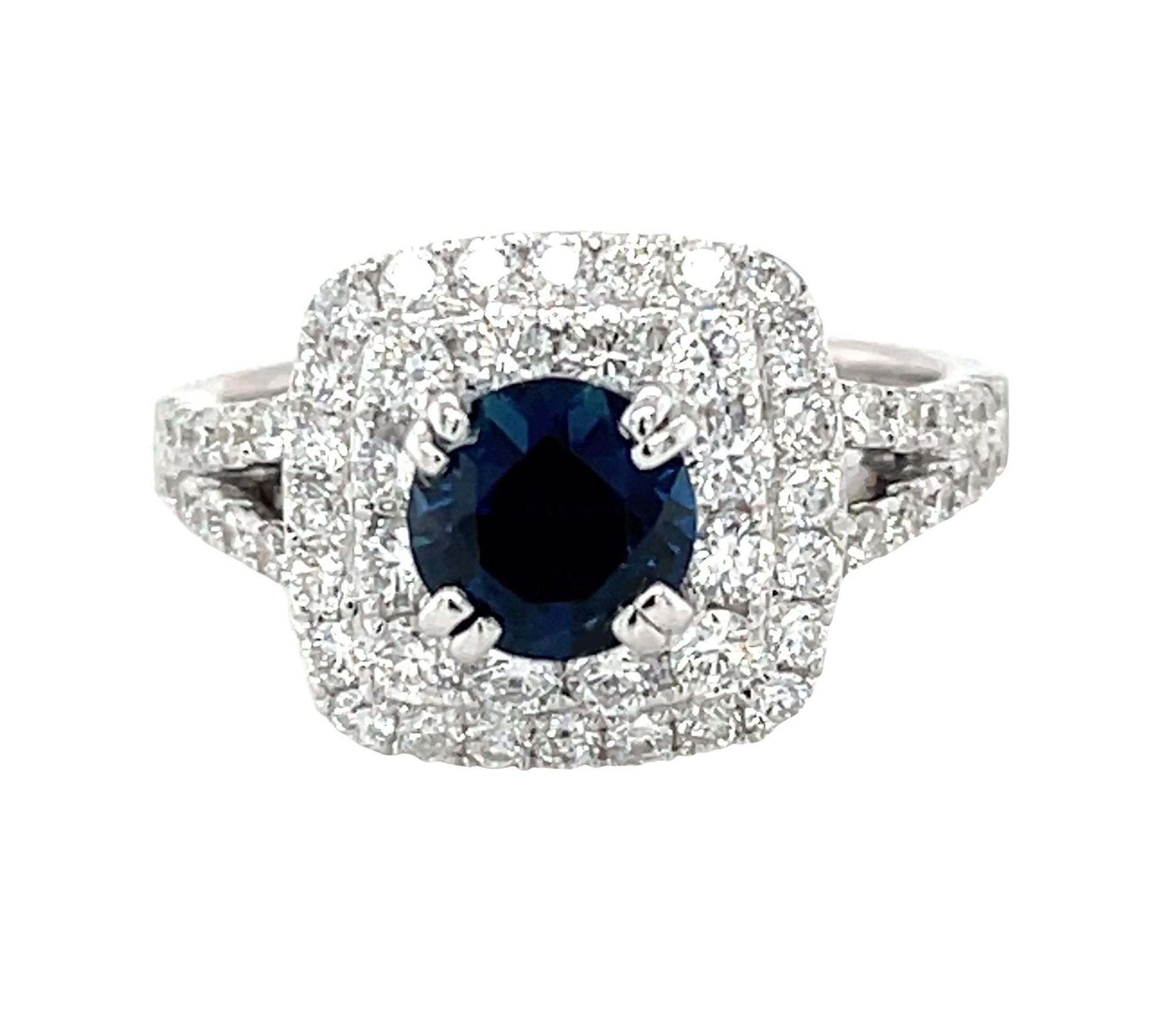 This beautiful cocktail ring features a gorgeous 1.15 carat round blue sapphire framed by a double halo of sparking diamonds! The brilliant white diamonds continue down each side of the elegant split shank of this stunning 18k white gold ring. Blue