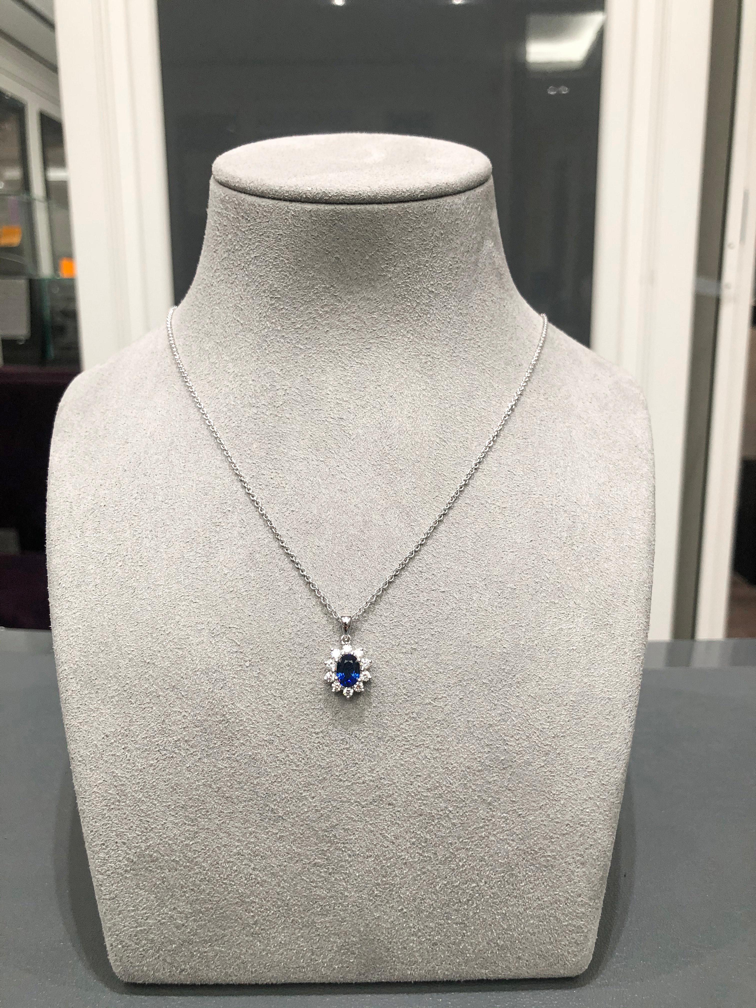 A stylish and simple pendant necklace showcasing a 0.86 carat oval cut blue sapphire, accented by round brilliant diamonds in a floral motif style. Diamonds weigh 0.35 carats total. Made with 18K White Gold, 16 inches in Length.

Style available in