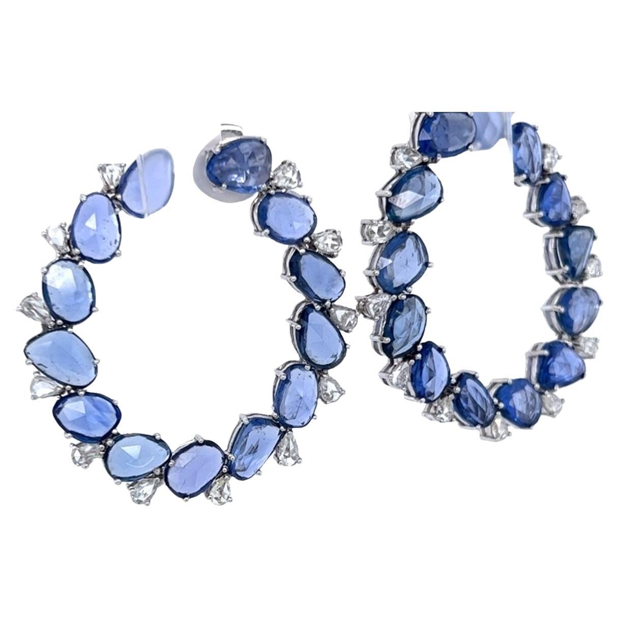 Vibrant blue sapphire and diamond half-hoop / C Shape circle stud earrings in 18 karat white gold. The 26 sapphires are multi-shape and weigh 18.79 carats in total. Set between each sapphire is 24 small pear shape white diamonds weighing 1.81 carats