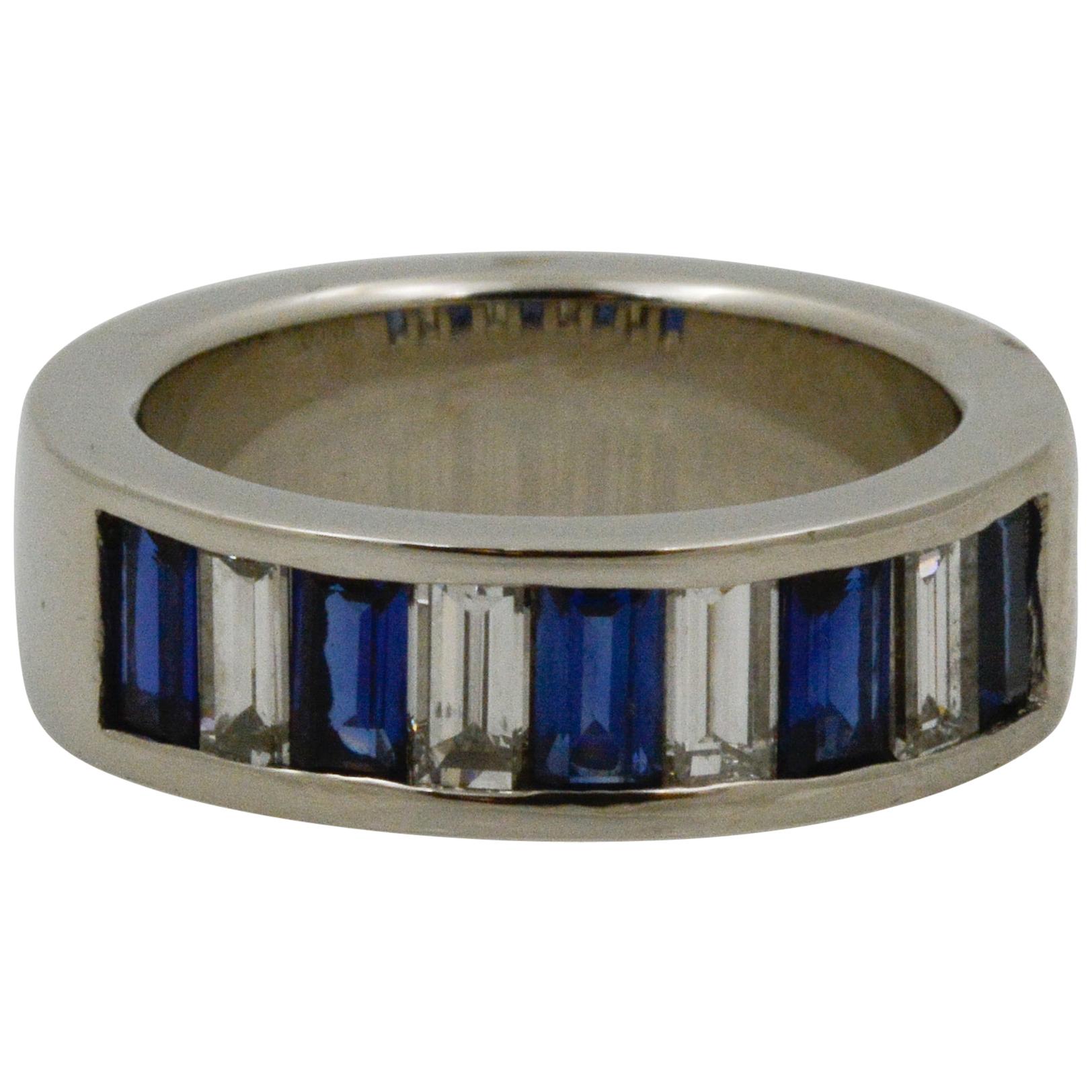 This platinum band ring features four baguette diamonds weighing an approximate combined 0.84 carats with FG coloring and VS clarity, and five baguette blue sapphires weighing an approximate combined 1.30 carats. The ring is a size 6. 