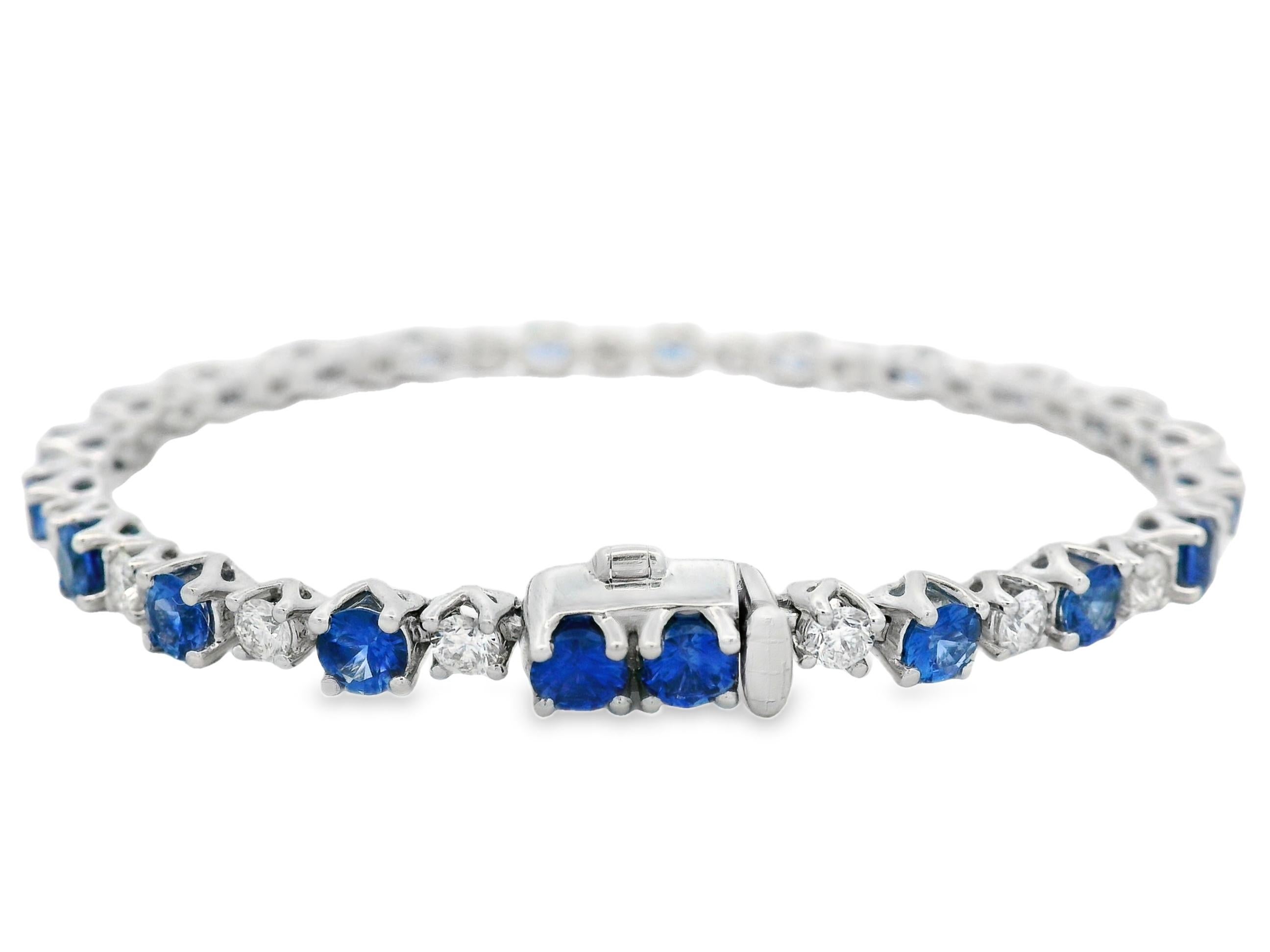 Esta elegante pulsera de tenis presenta una secuencia rítmica de zafiros azules vivos alternados con diamantes brillantes redondos, engastados en oro blanco pulido de 14 quilates. El diseño destaca 4,18 quilates de zafiros azules ricamente saturados