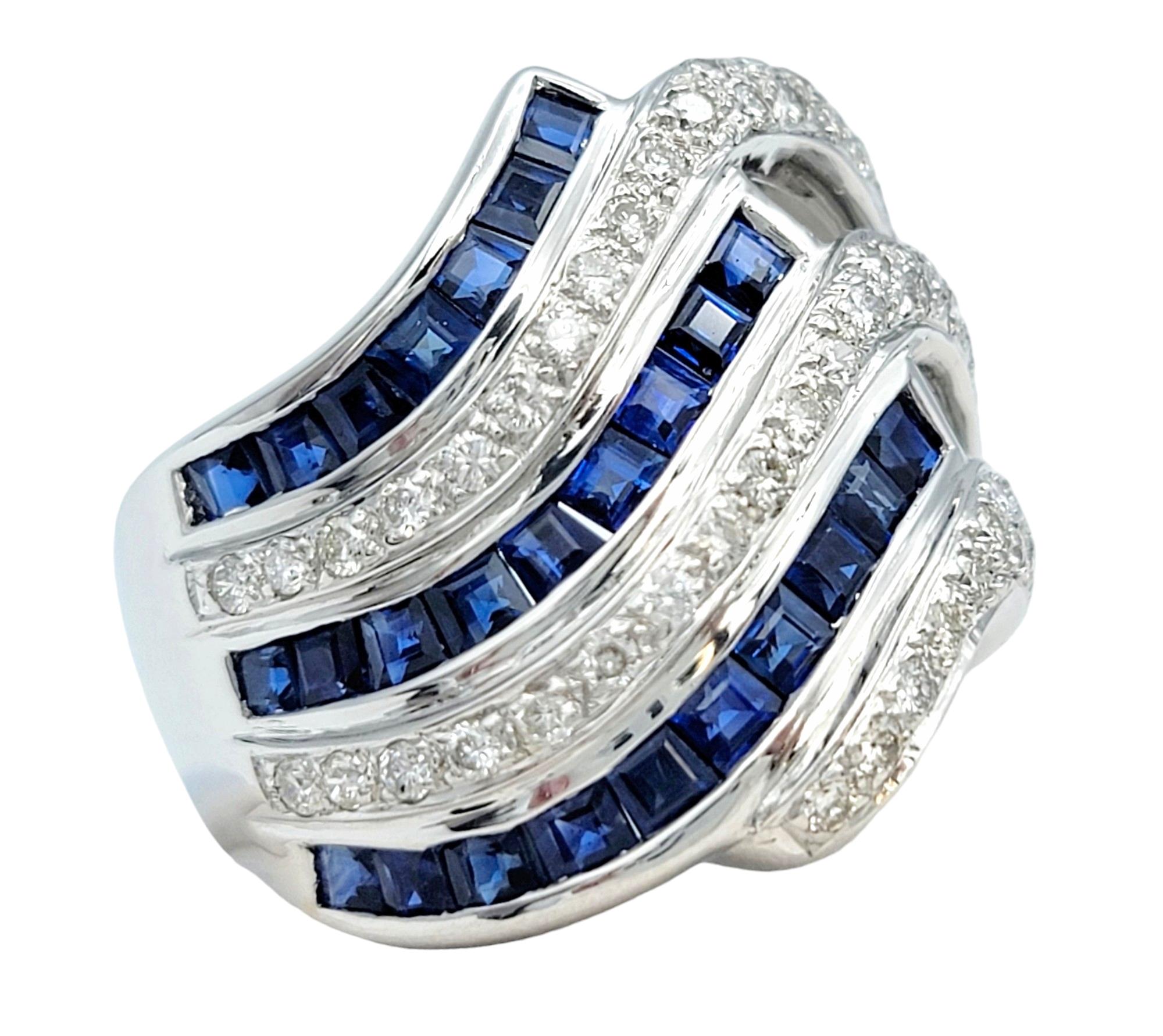 Ring Size: 7.5

This gorgeous ring, set in luxurious 18 karat white gold, is a distinctive and eye-catching piece with a unique wave design. The slightly slanted wave pattern alternates rows of princess-cut blue sapphires and round diamonds,