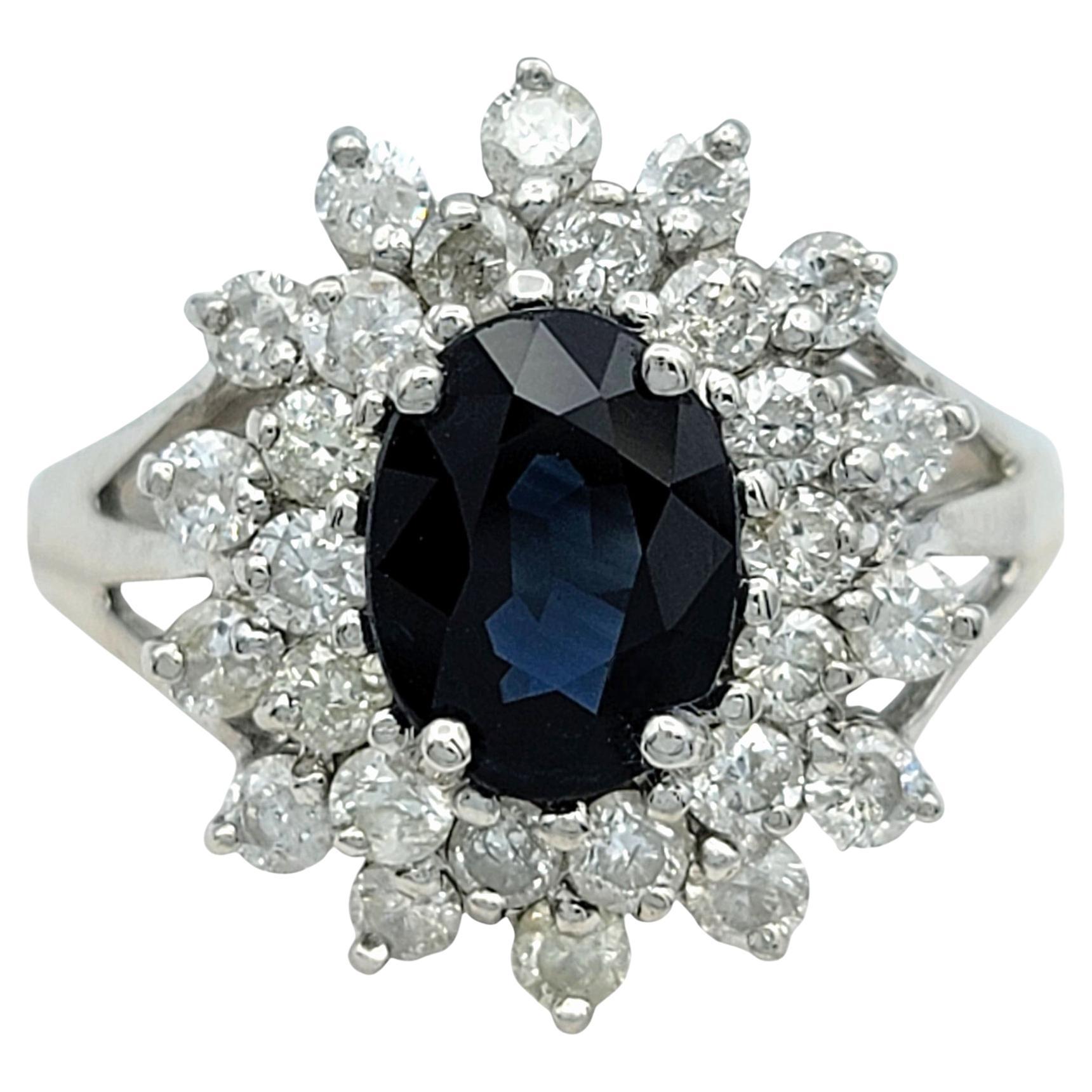 Ringgröße: 7 

Eleganz erblüht mit diesem atemberaubenden Cocktailring, in dessen Zentrum ein blauer Saphir im Ovalschliff thront. Das satte, tiefe Blau des Saphirs wird durch einen strahlenden doppelten Halo aus funkelnden Diamanten, die in einem