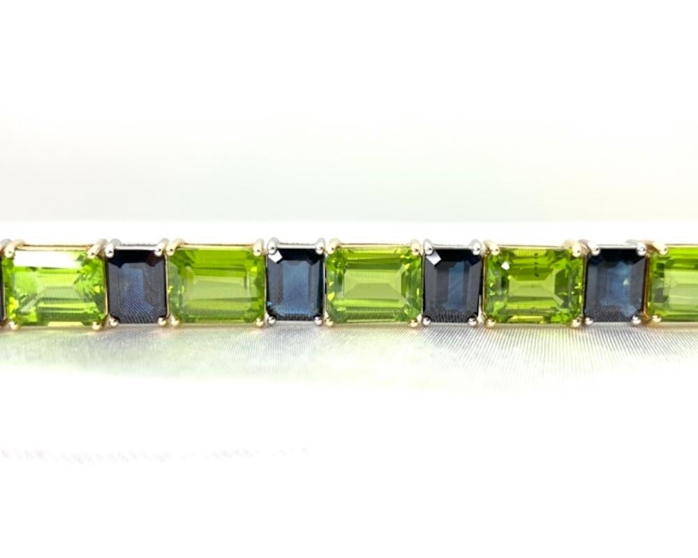 Modern, rectangular faceted sapphires in cool blue are paired with warm green peridot in this stunning 18k gold tennis bracelet. This gorgeous selection of vibrant gemstones weighs over 75 carats in total, making it a considerably rare collection,