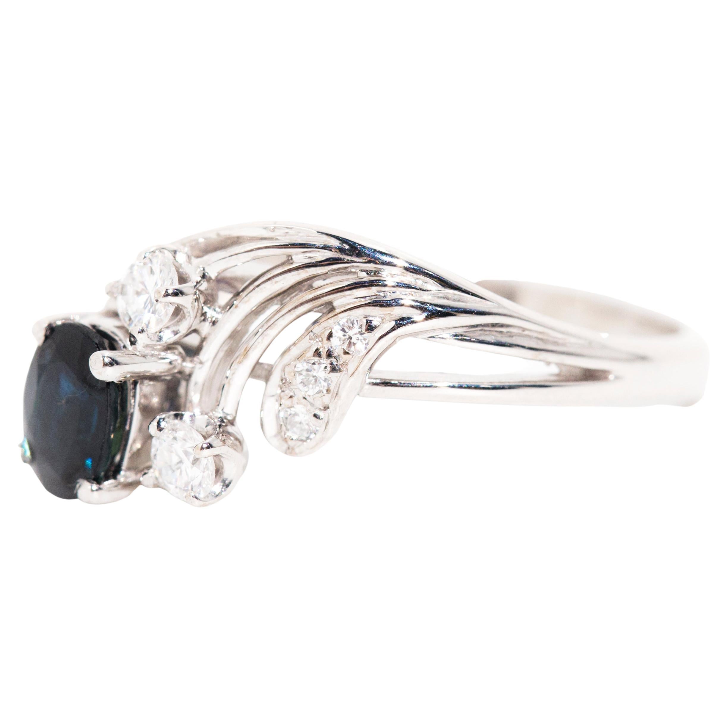 Forged in 18 carat white, this whimsical vintage piece is a delight for lovers. The Antoinette Ring fearers an ethereal diamond-embelished wing swooping up from one side, ending in a clutch of feathers swept around a deep blue sapphire perched upon