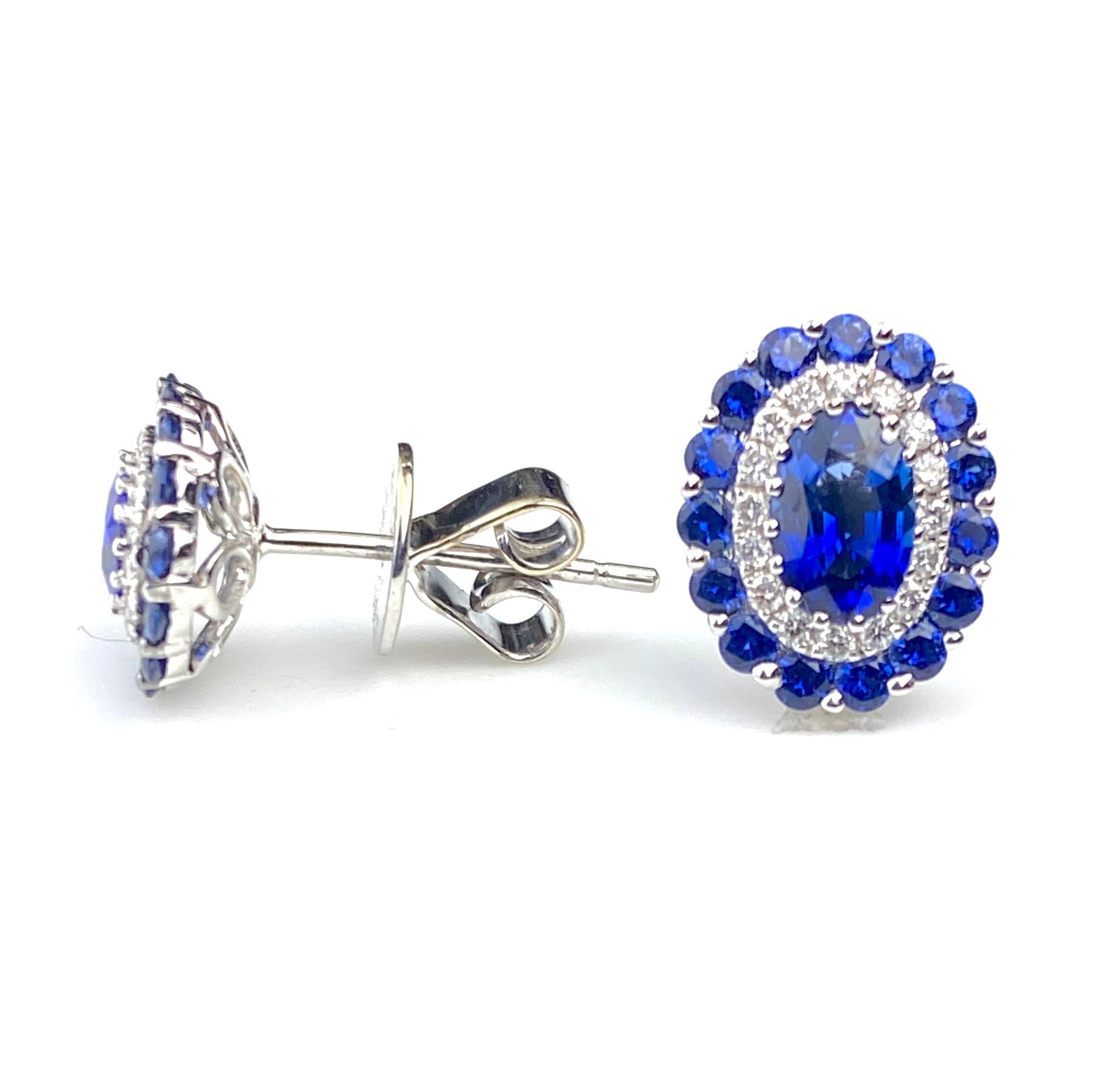 Oval cut blue sapphire gems surrounded by consecutive halo's of white diamonds and blue sapphires.  Comprising 1.85ct total of blue sapphires and 0.19ct total of diamonds. Set in 18kt white gold stud setting with medium backing. 