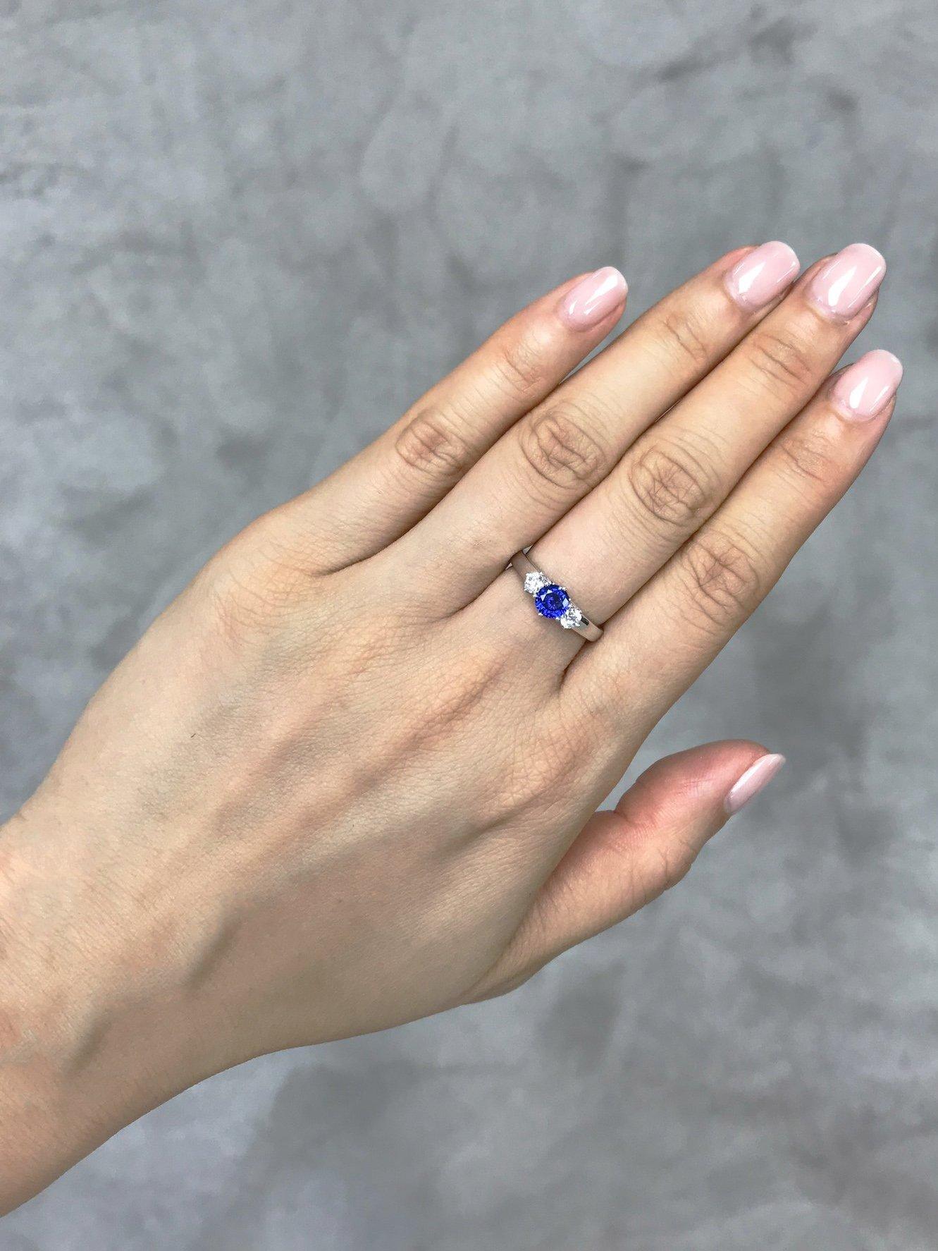 This brilliant three-stone engagement ring is set in 18K white gold. The center stone, a 5mm round cut natural blue sapphire is set in a four prong setting and adorned by two round cut 3mm natural white sapphire. 

Specifications:
5mm Round Cut