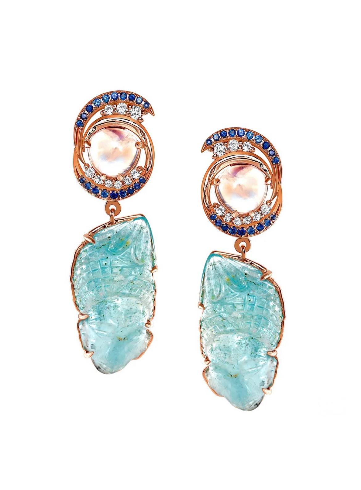 These awe-inspiring 18K rose gold earrings, dazzles with two 15.21 carats of carved Aquamarines and 6.48 carats of rainbow Moonstones. Scintillating halo of Ceylon sapphires totaling 0.76 carats and white diamonds totaling 0.54 carats adds style and